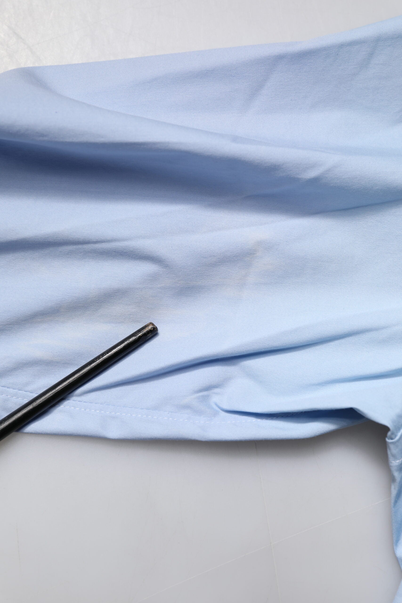 A light blue cotton formal shirt with a gold design on the front, displayed against a white background