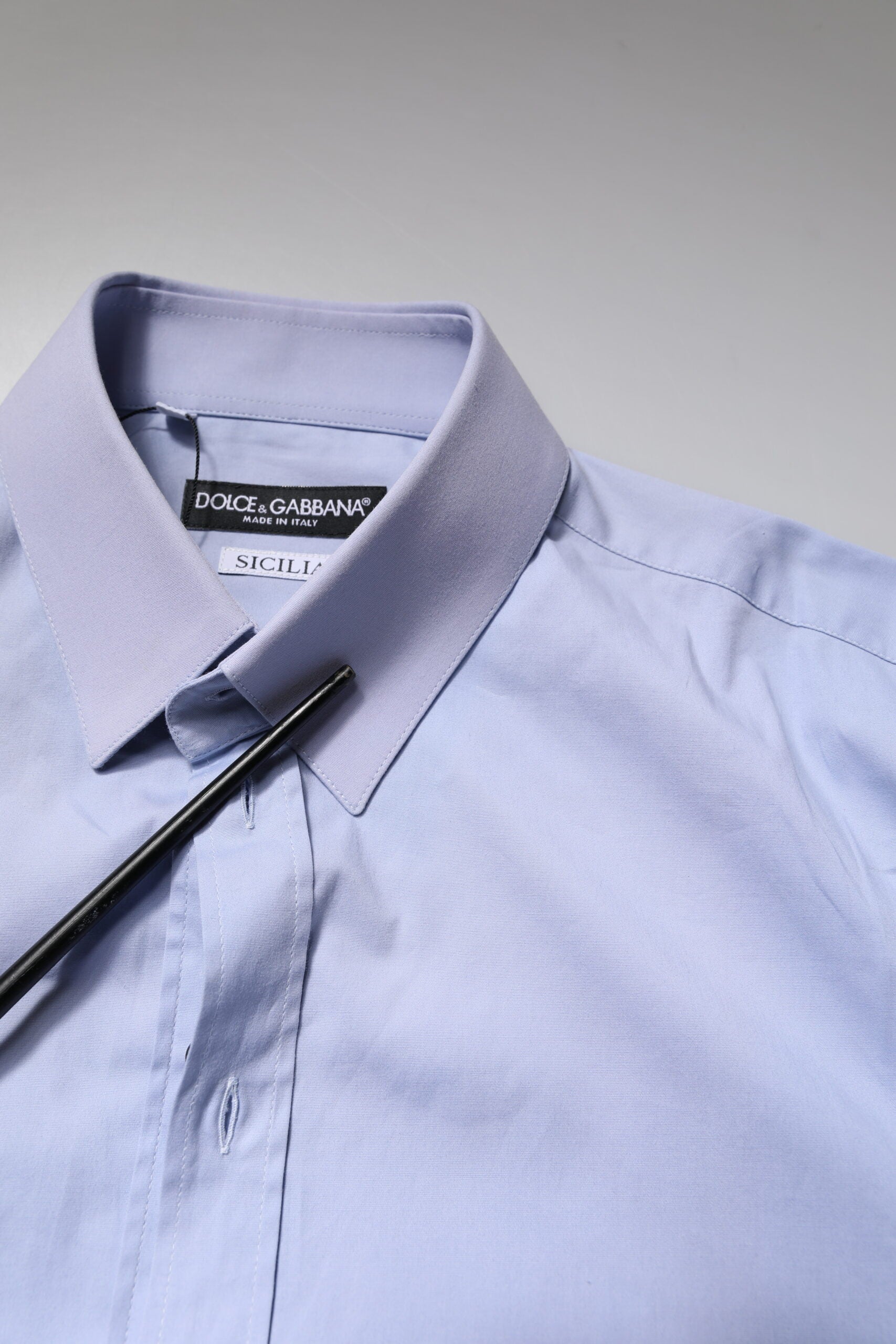 A light blue cotton dress shirt with a collar and black label on the inside