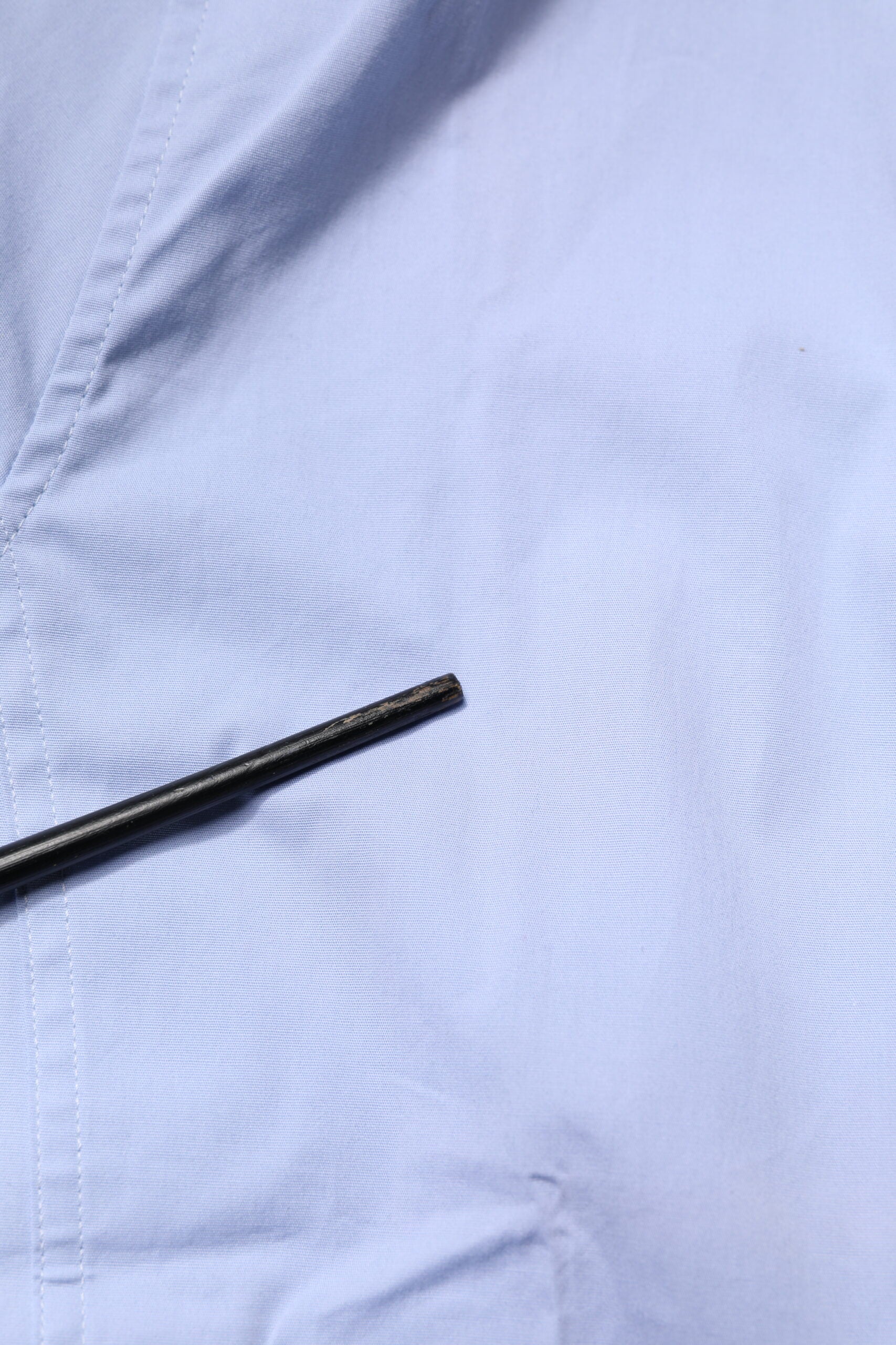 A light blue cotton dress shirt with a black button
