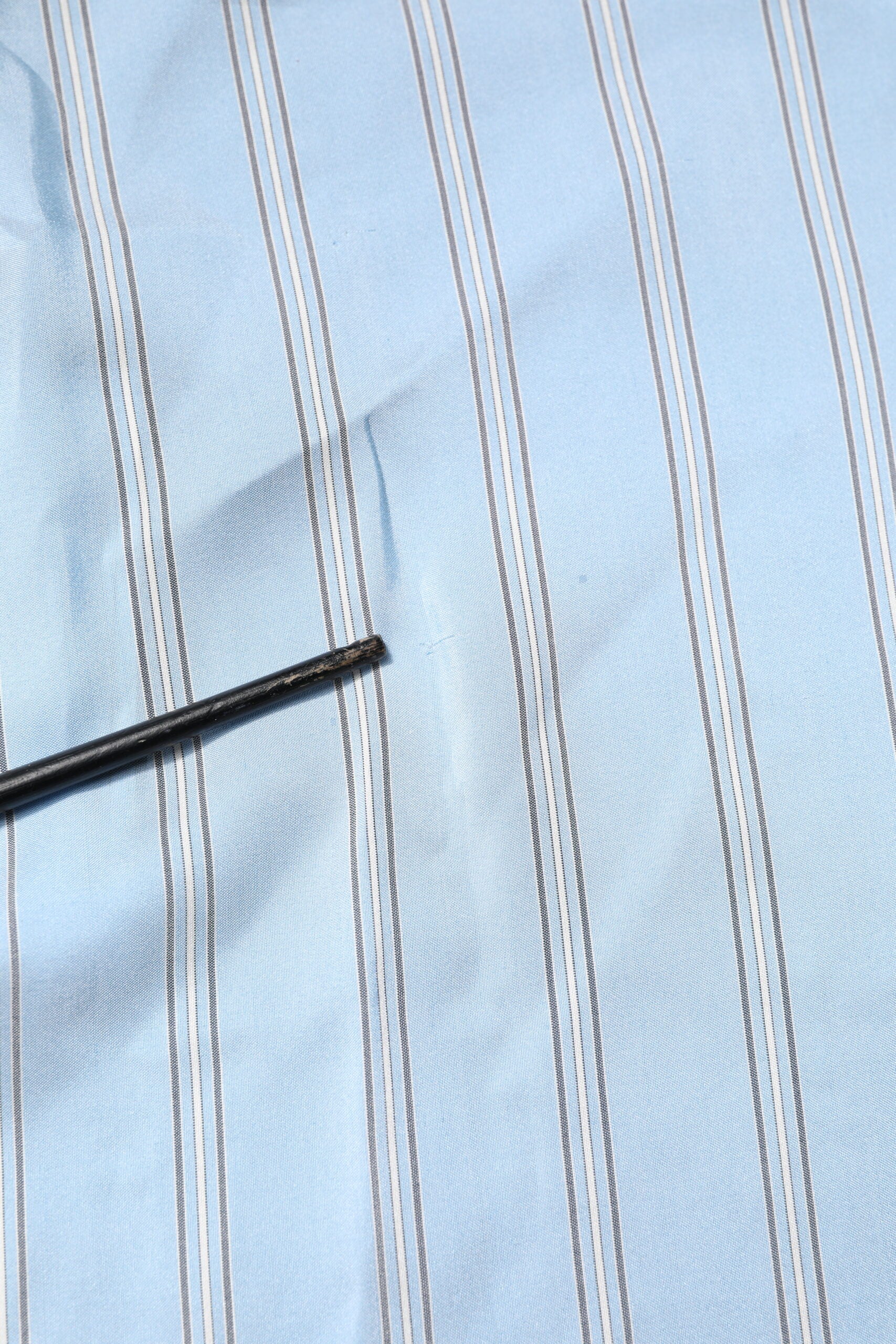 A light blue striped dress shirt with a black button
