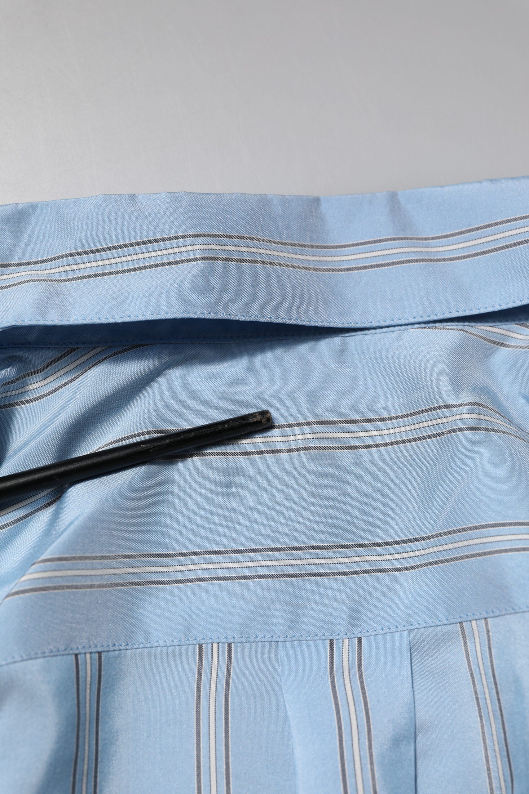 A light blue striped dress shirt with a black tie
