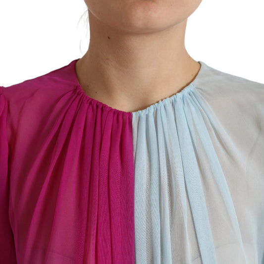 A woman wearing a light blue silk two tone midi dress with pink and white accents