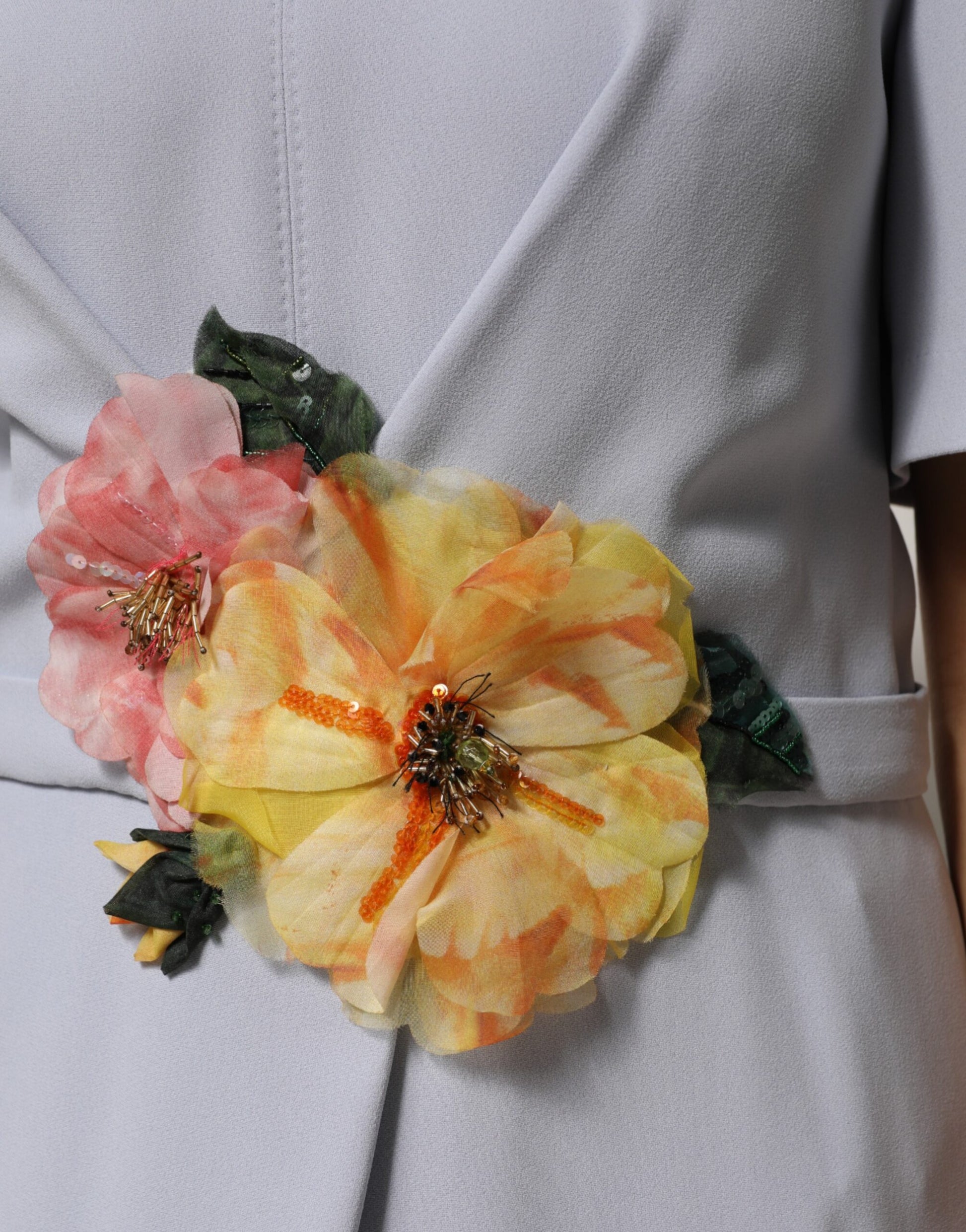A floral applique dress with a vibrant flower brooch on the shoulder