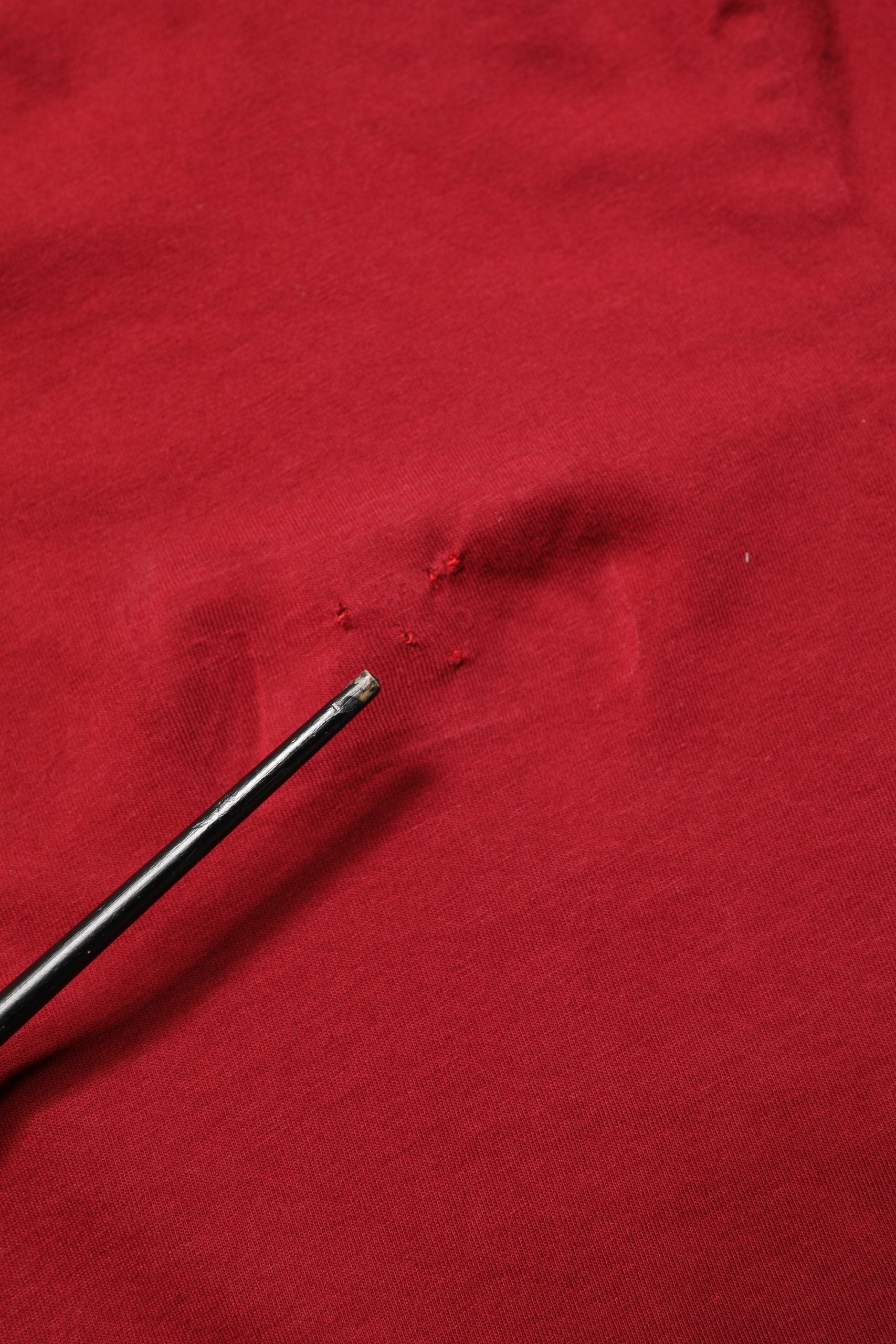 Black needle in red fabric
