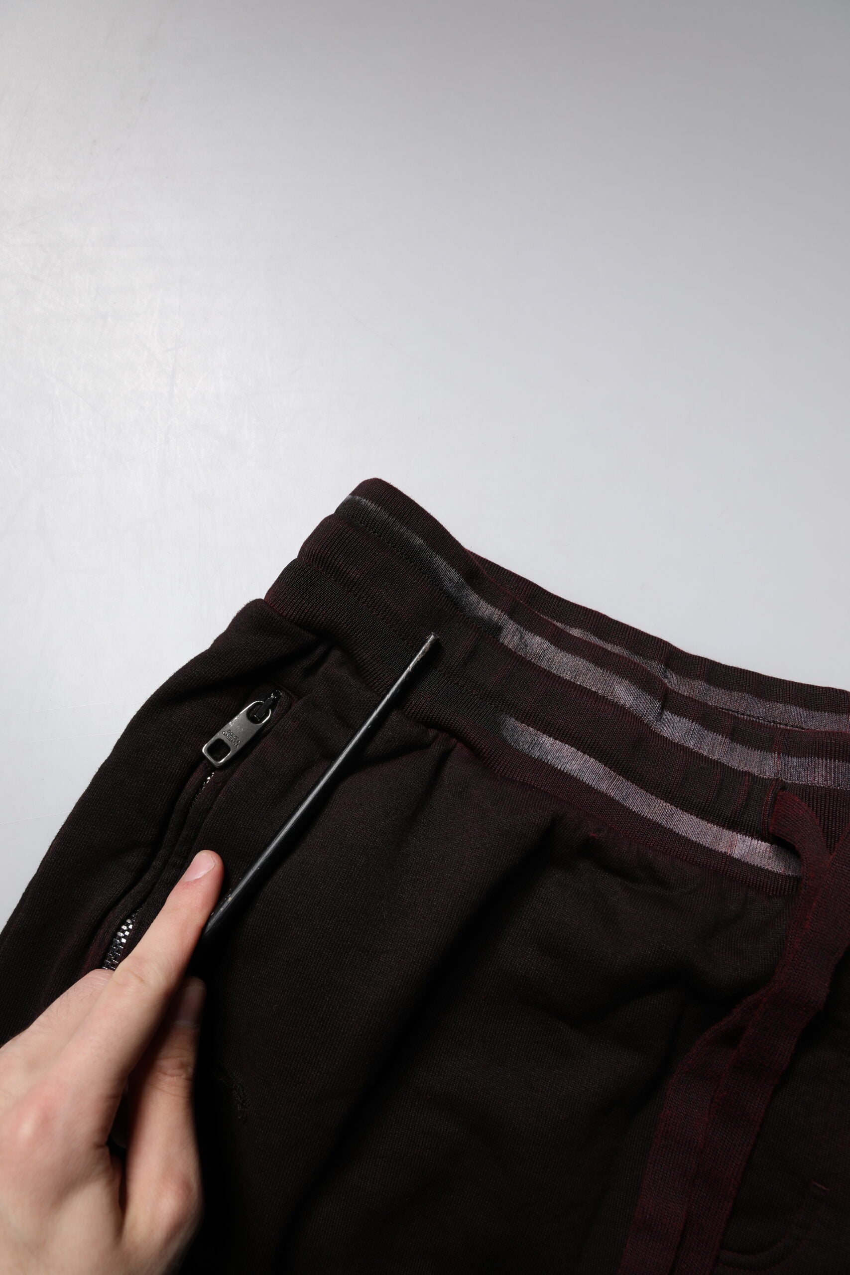 Hand holding a pin in front of a pair of pants