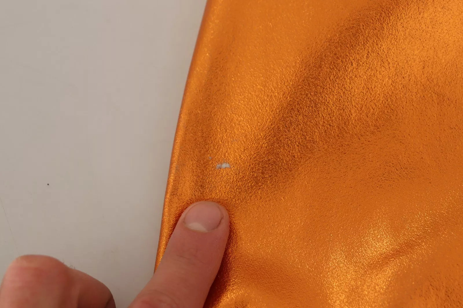 A sleeveless sheath dress in metallic orange, with a shiny texture