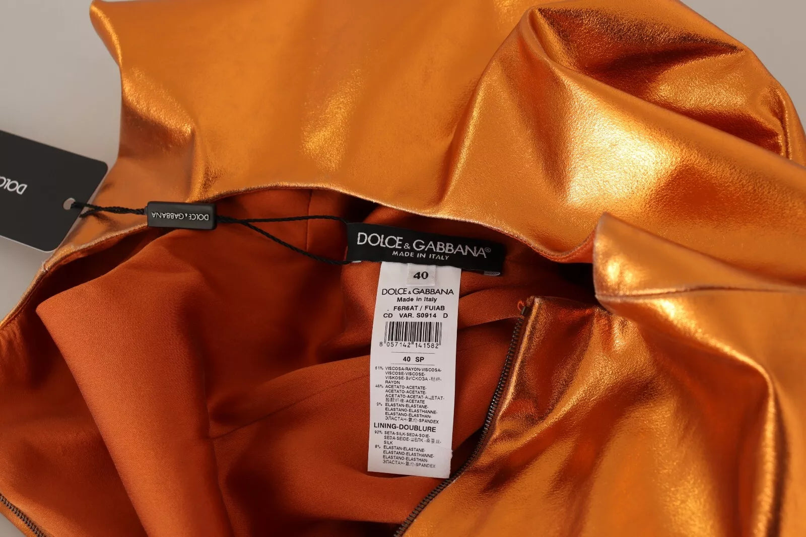 A sleeveless orange dress with a metallic sheen, featuring a tag indicating it is from the brand Dolce & Gabbana
