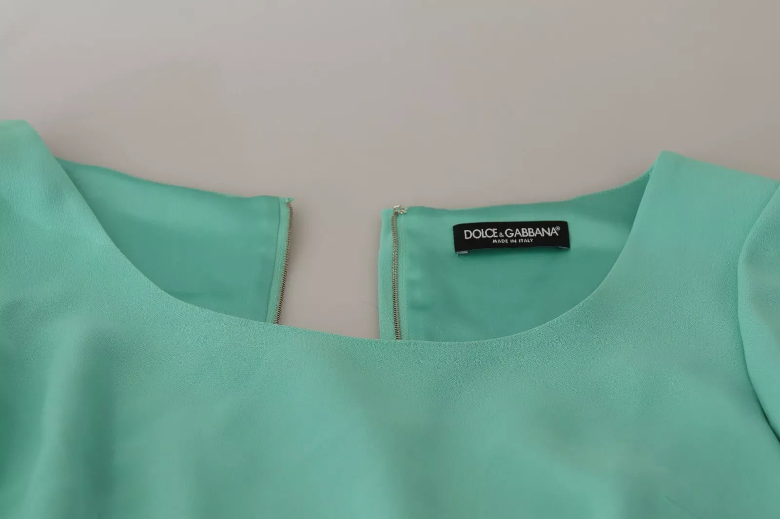 A mint green sheath dress with a square neckline and midi length, featuring a label on the inside