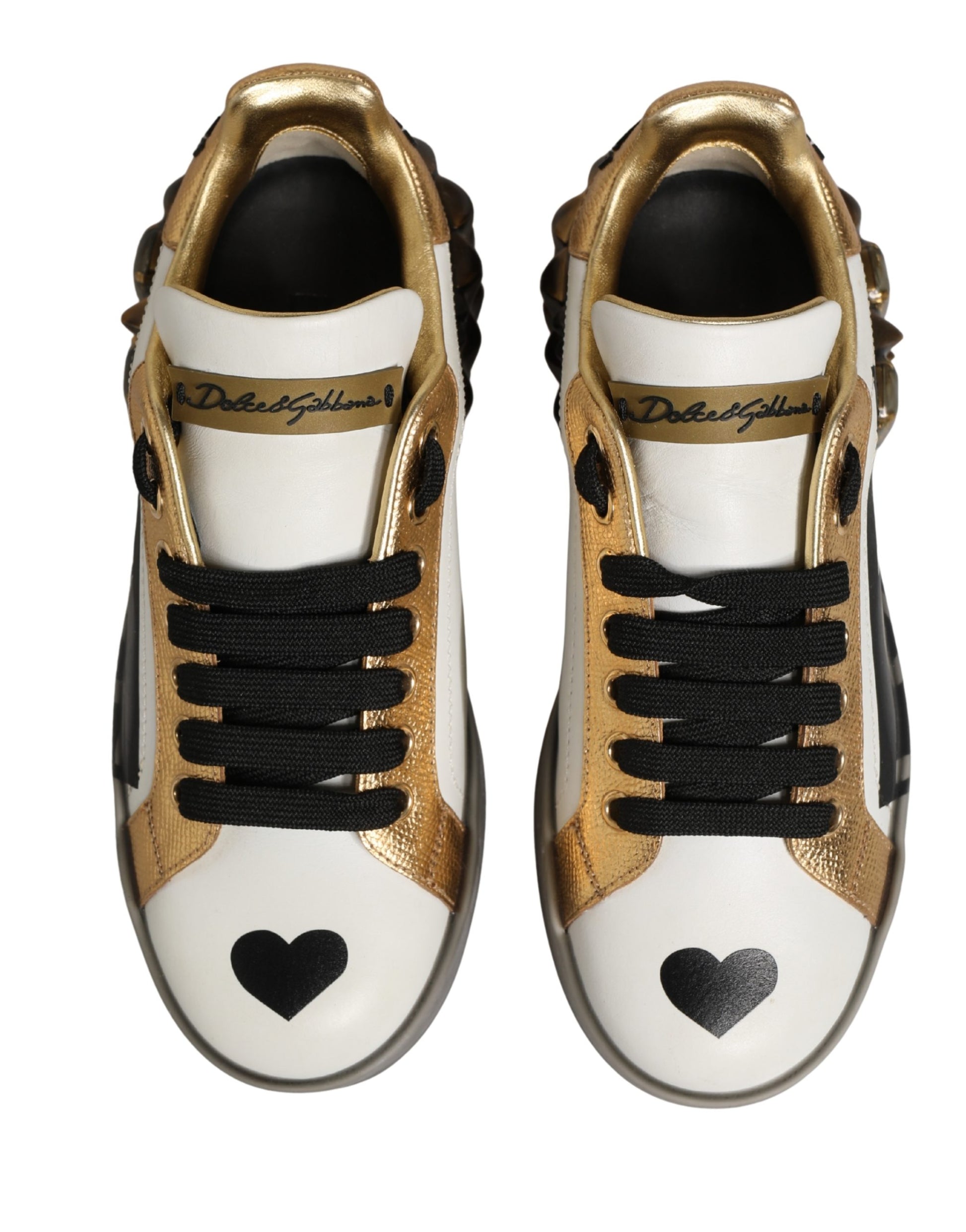 Pair of white sneakers with gold and black accents, featuring heart-shaped studs