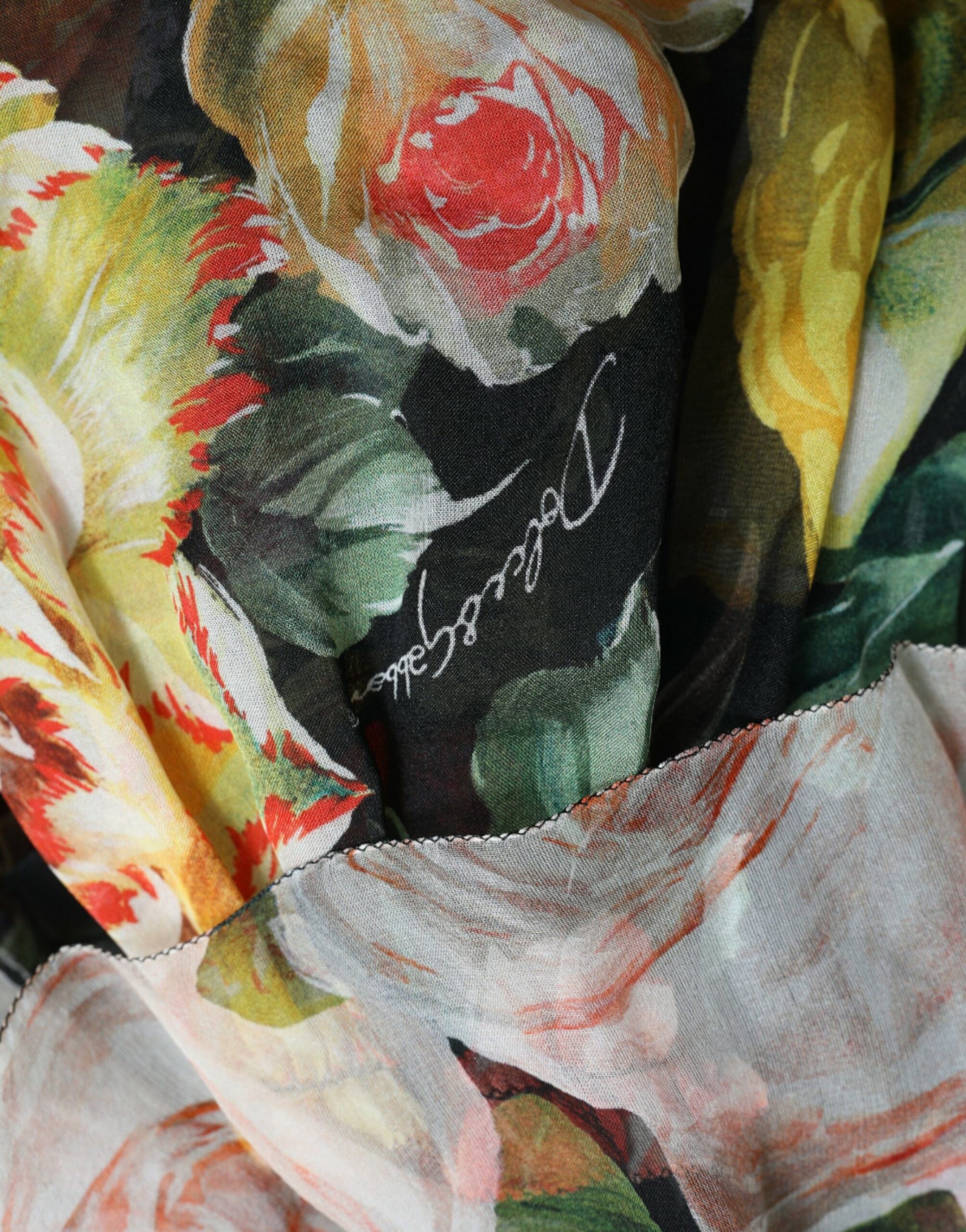 A colorful floral chiffon dress with tiered design and a signature on the front