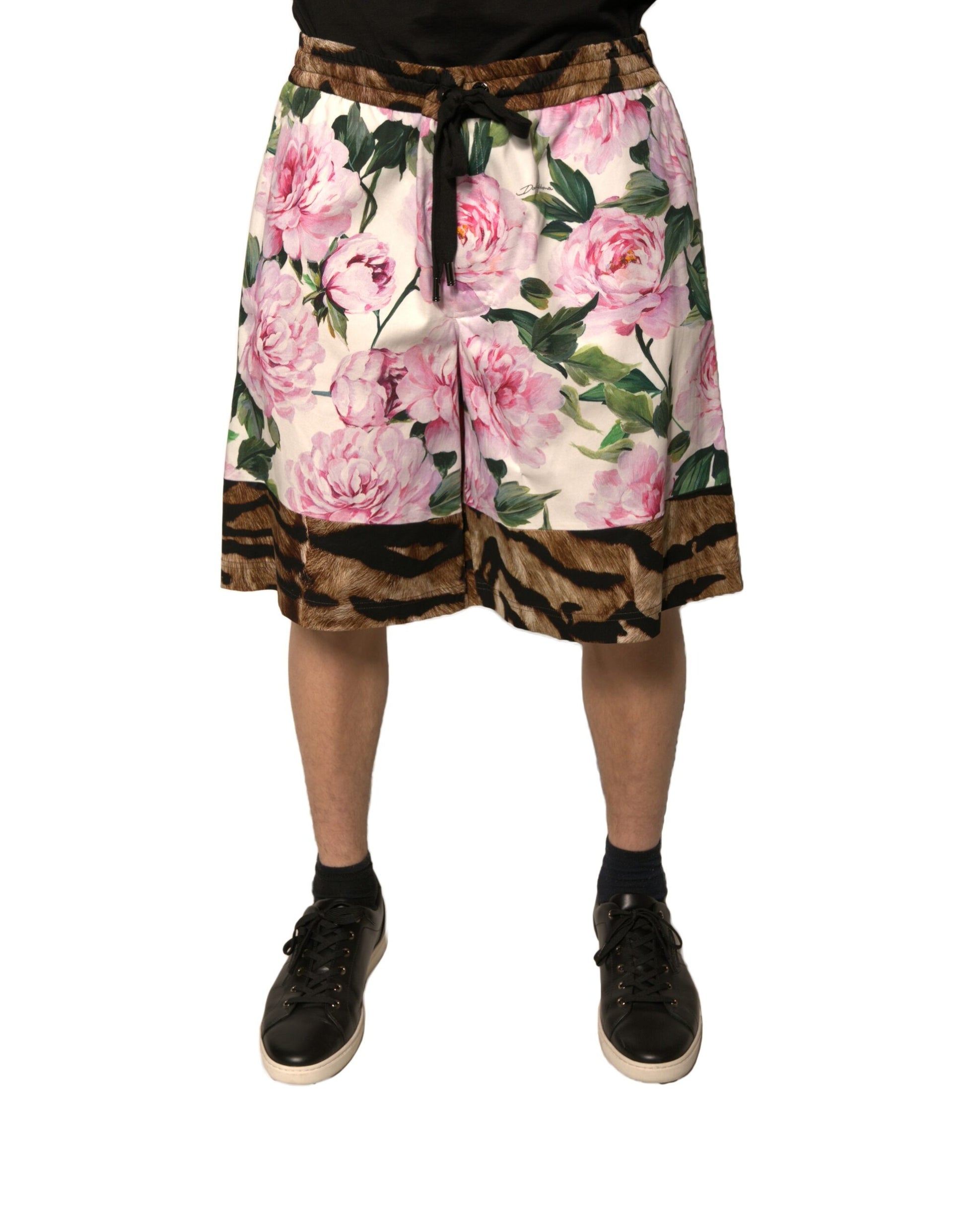 A pair of men's shorts with a floral pattern featuring pink and green flowers on a brown background
