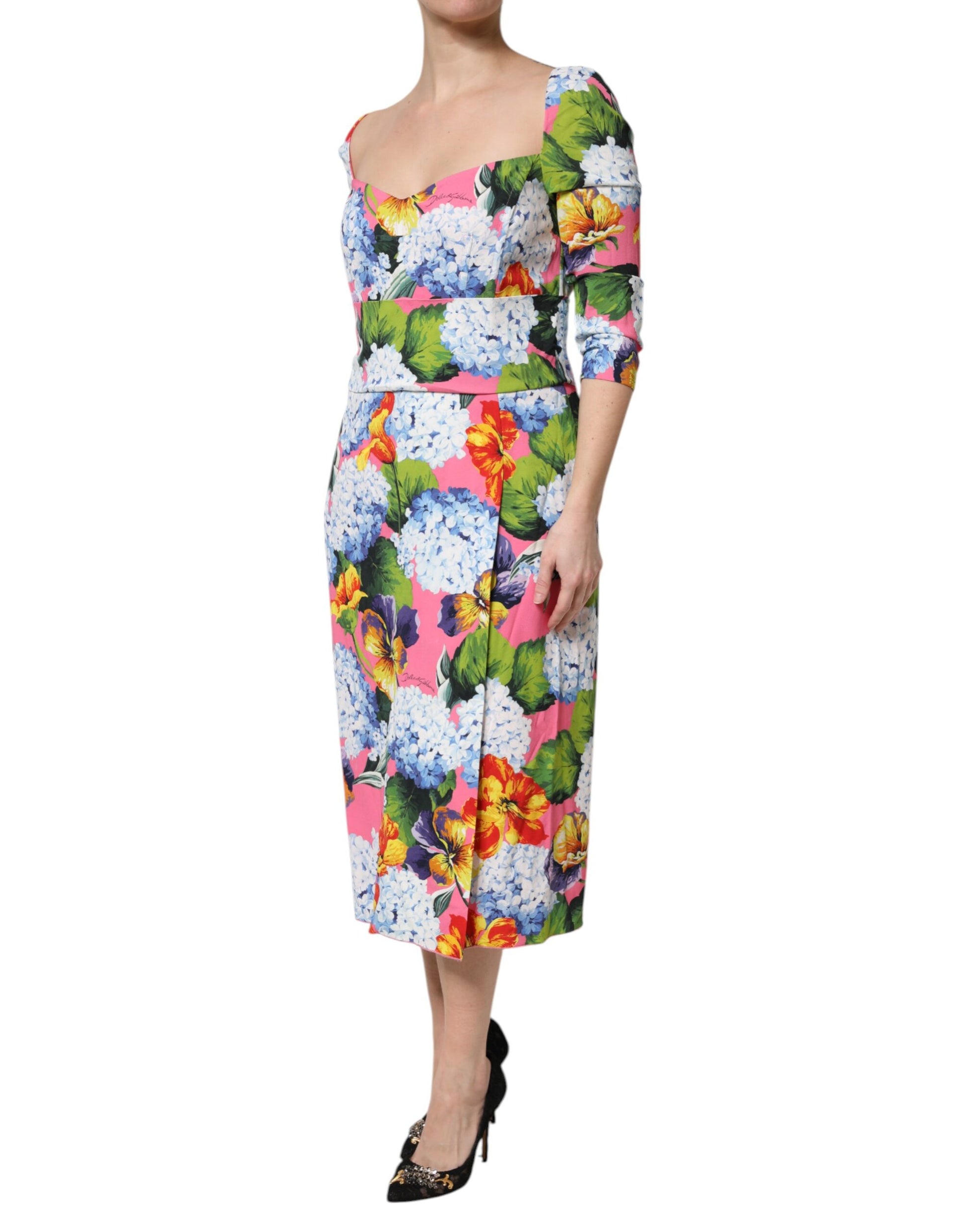 A woman wearing a multicolored floral pleated midi dress with black heels