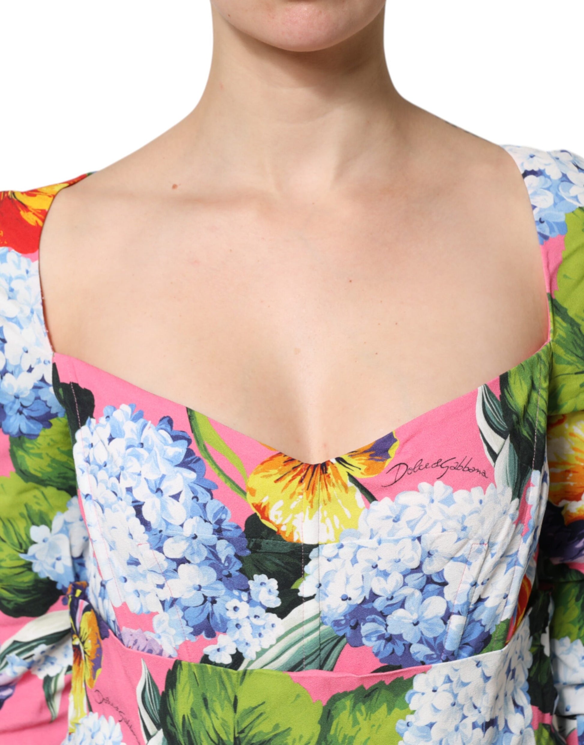 A woman wearing a colorful floral print midi dress with pleats