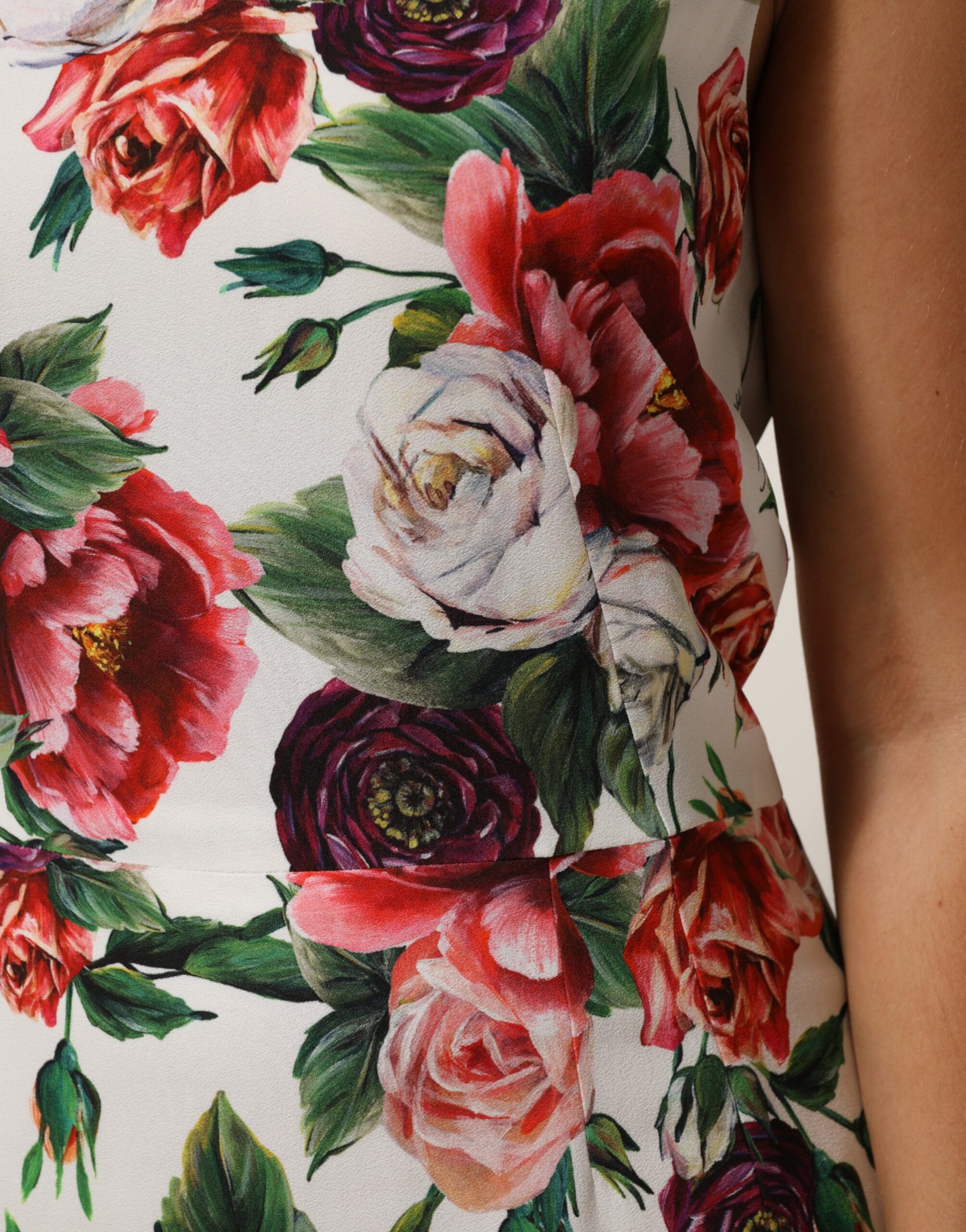 A sleeveless dress with a floral print, featuring red and pink flowers on a white background