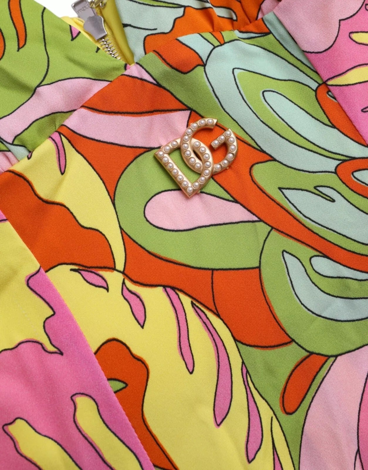 A colorful flared mini dress with a floral pattern, featuring a shiny gold buckle on the front