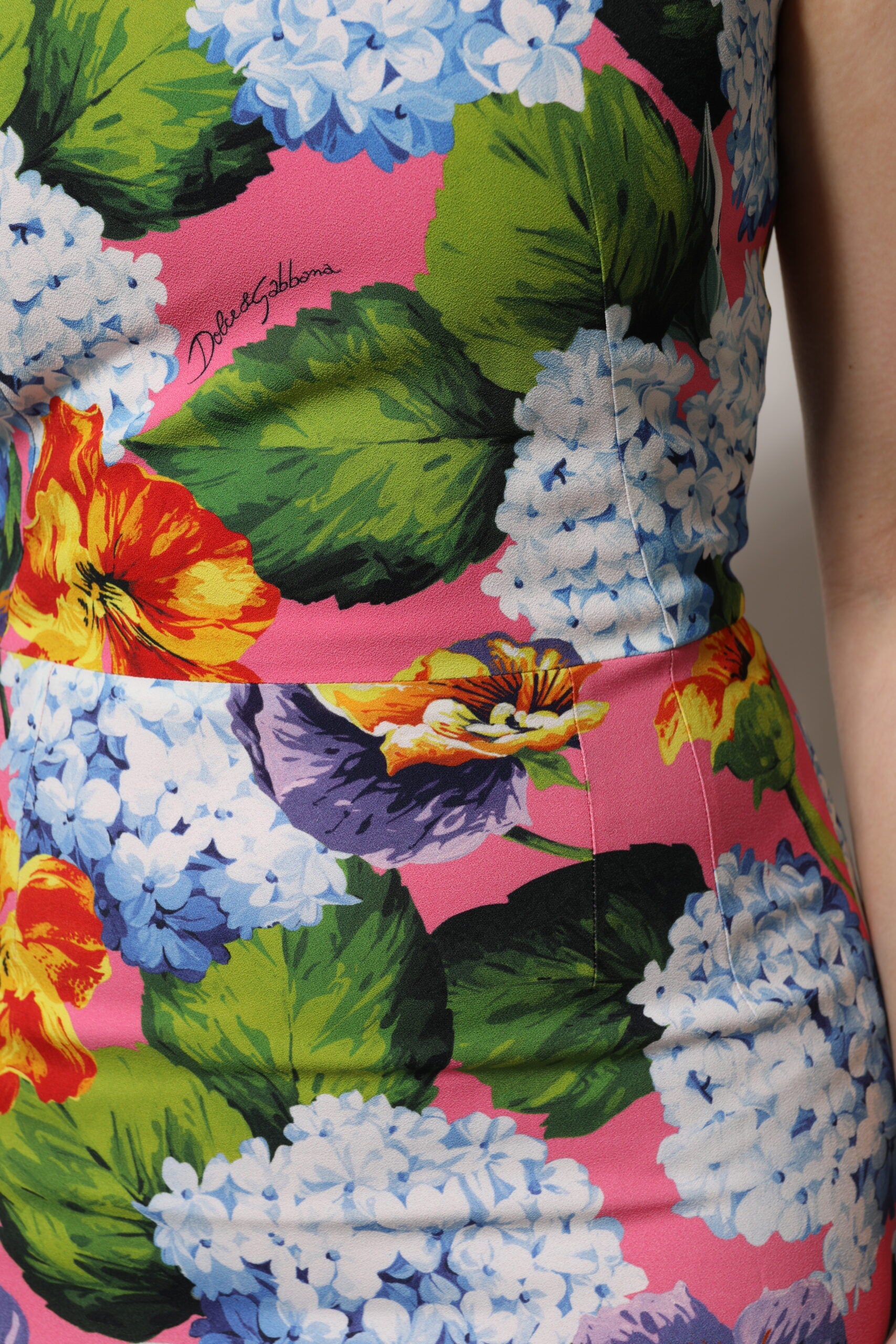 A sleeveless sheath dress with a floral pattern in shades of pink, blue, and green
