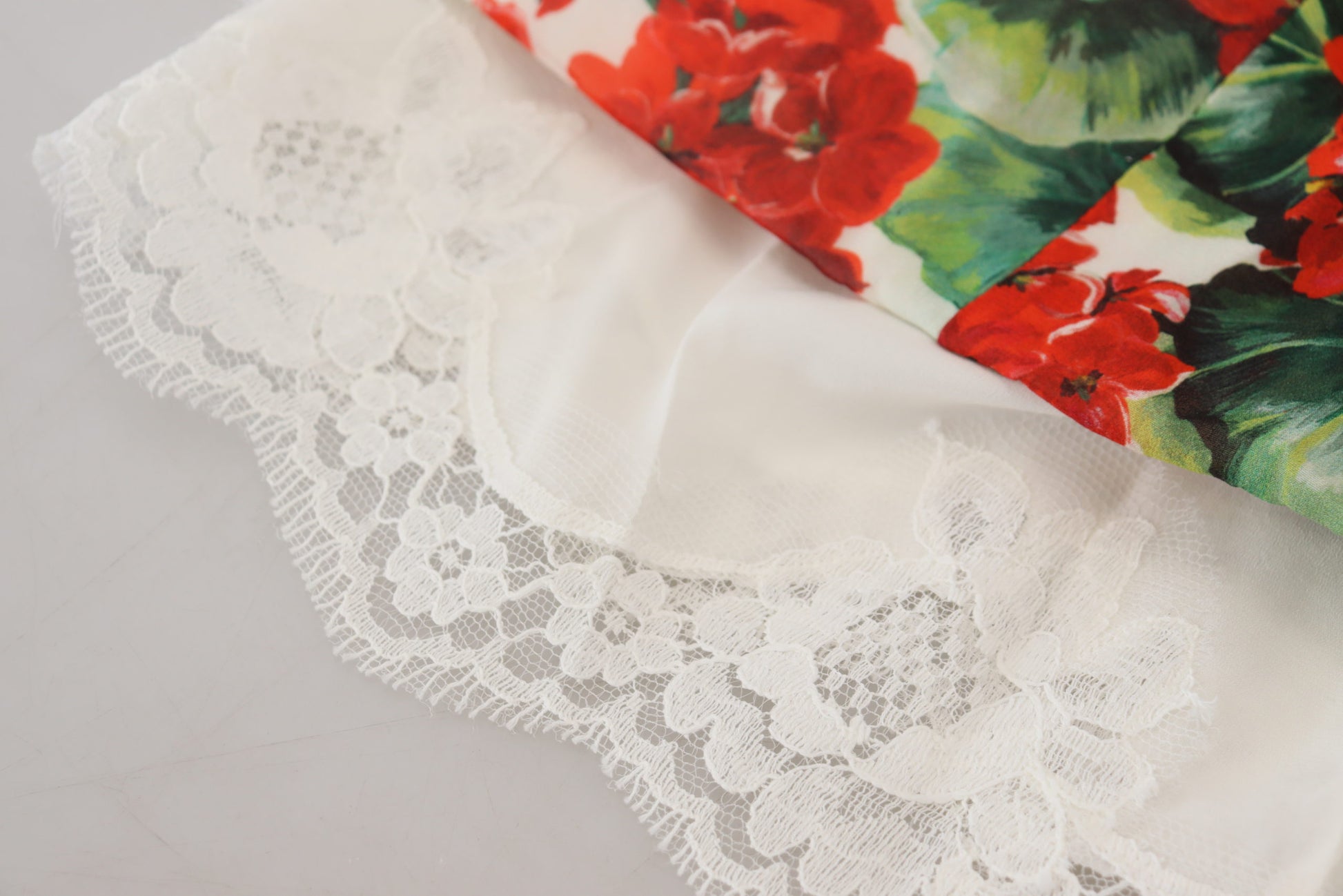 A lacy, white dress with a red and green floral pattern on the bodice