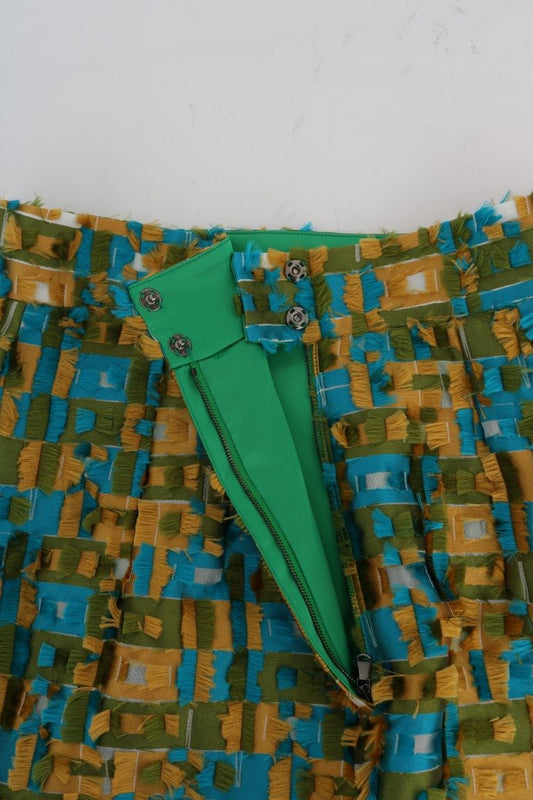 Green paper airplane in front of colorful fabric