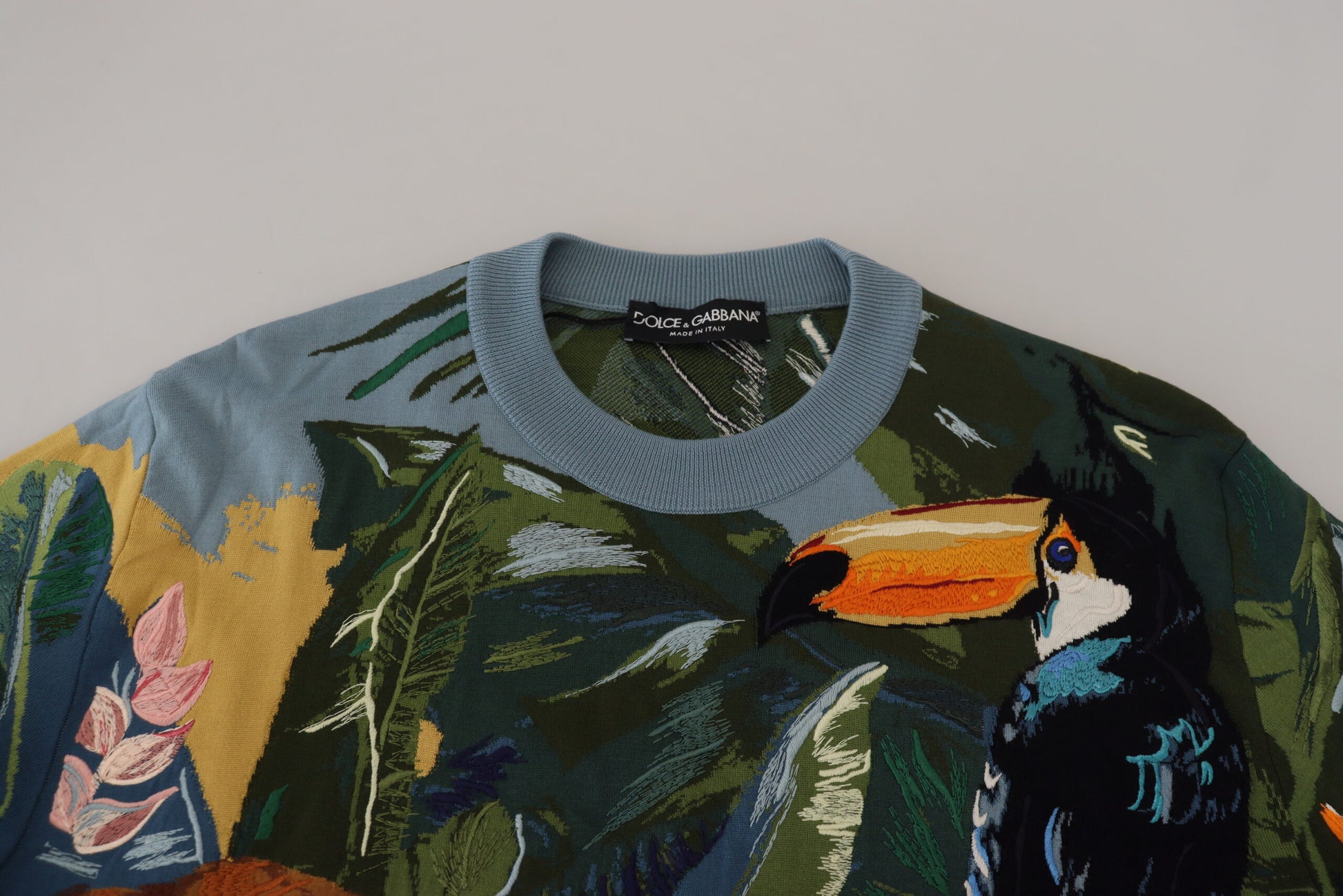 Knit sweater with colorful design featuring birds and foliage