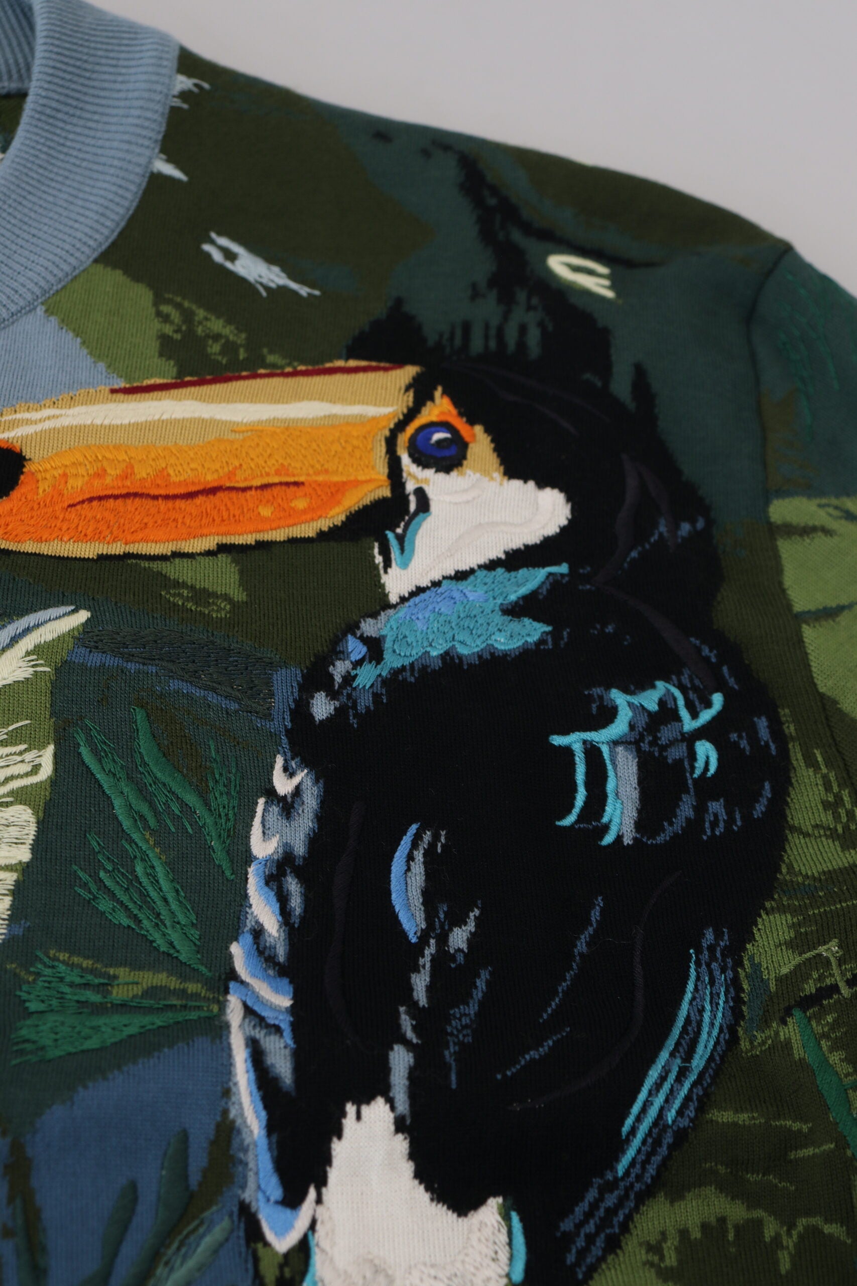 Colorful bird sweater with blue, green, and white feathers