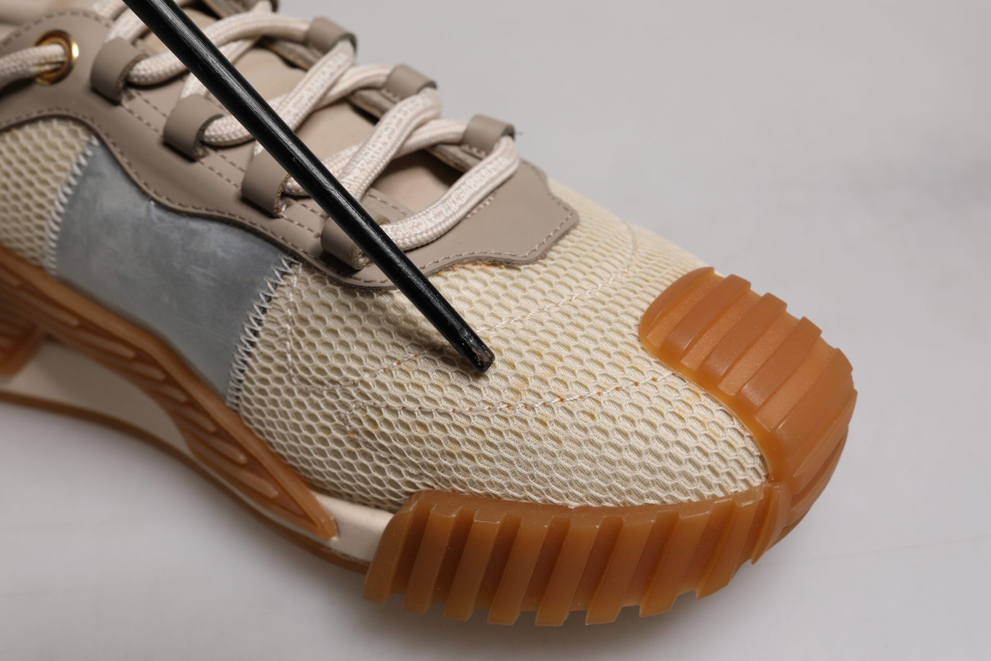 Tan sneaker with black laces and orange sole