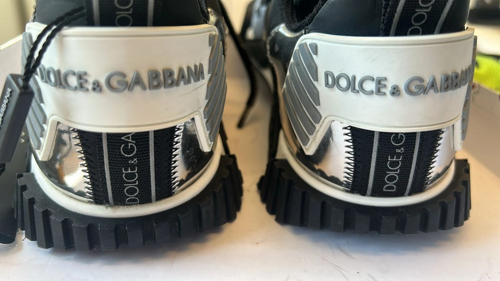 Pair of white sneakers with black soles and a logo on the side