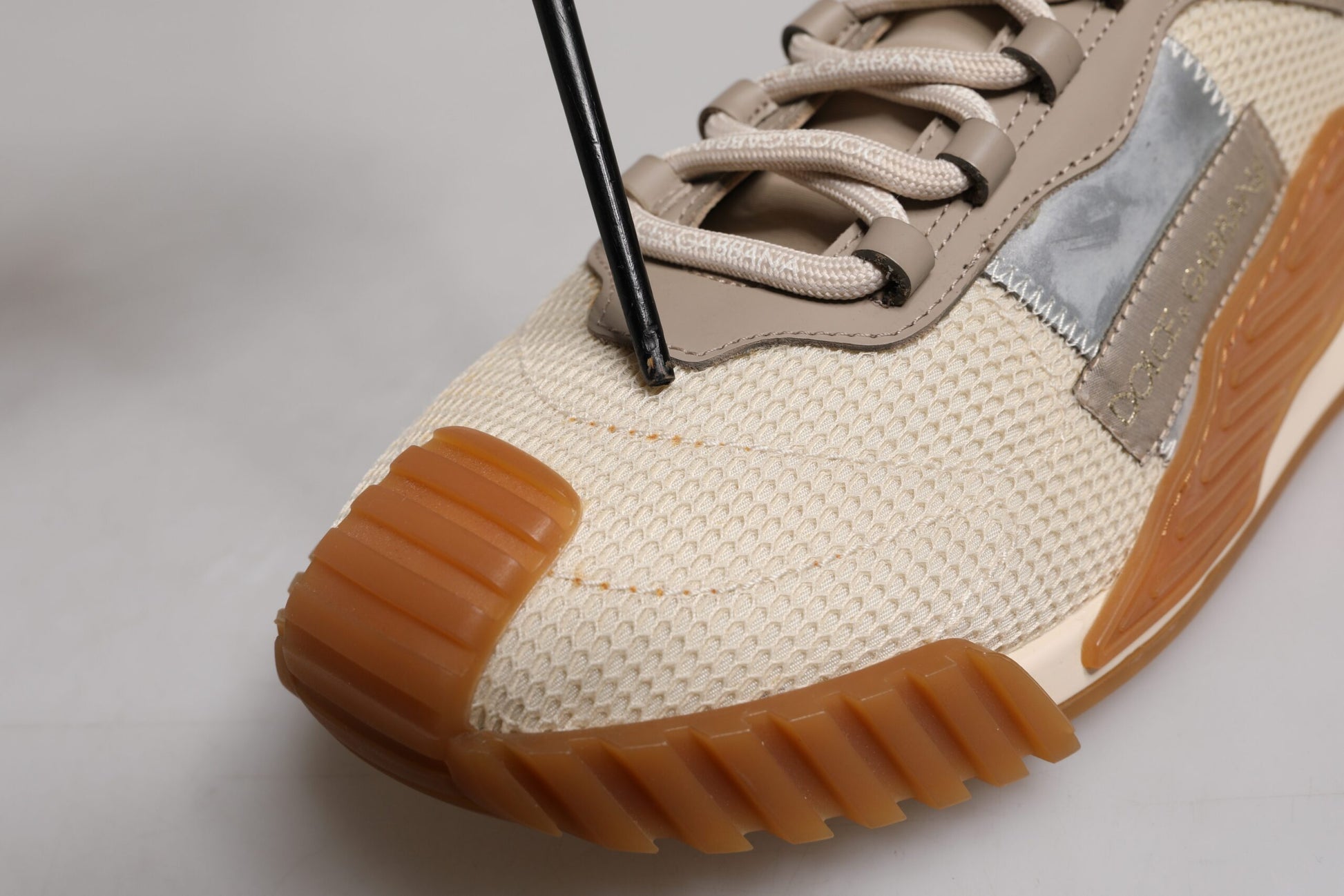 Tan sneaker with orange sole and laces