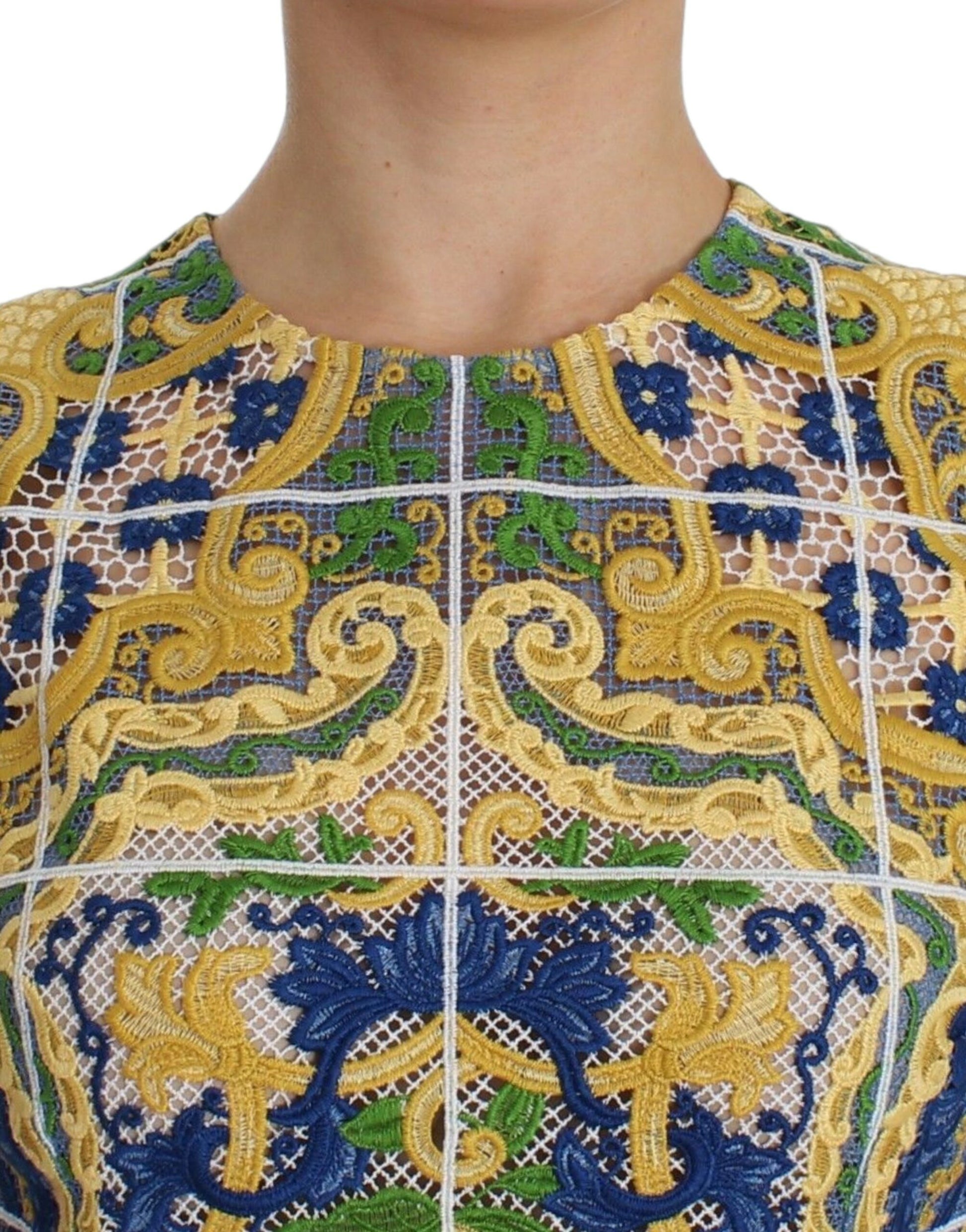 Decorative embroidered top with intricate patterns in blue, gold, and green on a white background
