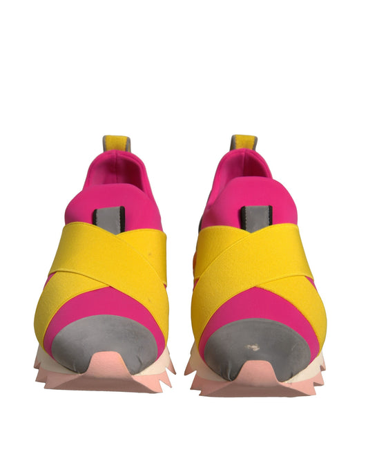 Pair of yellow and pink sneakers with spikes on bottom