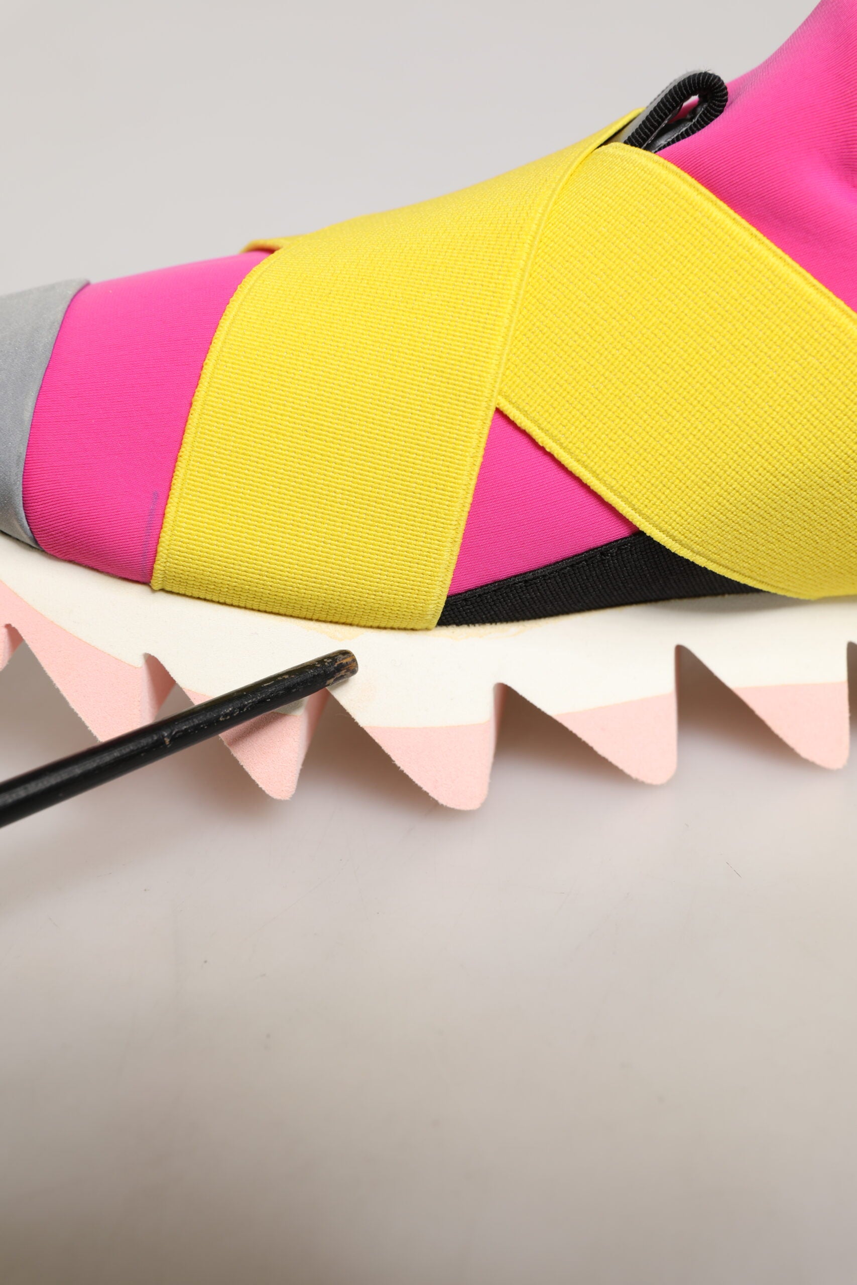 Pink, yellow, black shoe on a pink surface