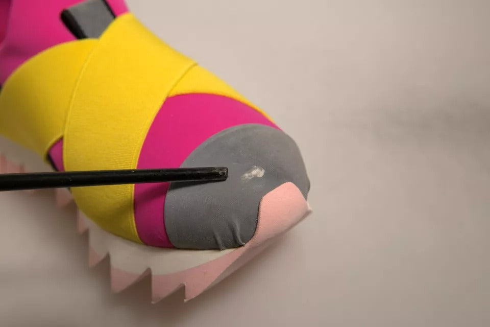Handheld toy with a pink body, gray head, and yellow feet