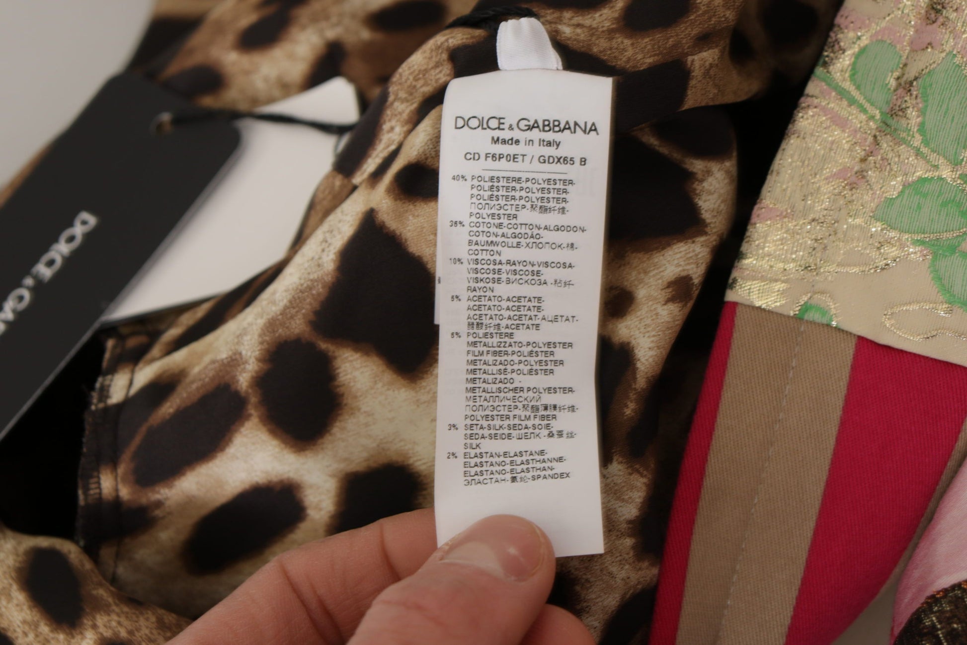 A person's hand holding a tag on a multicolored floral sheath dress by Dolce & Gabbana
