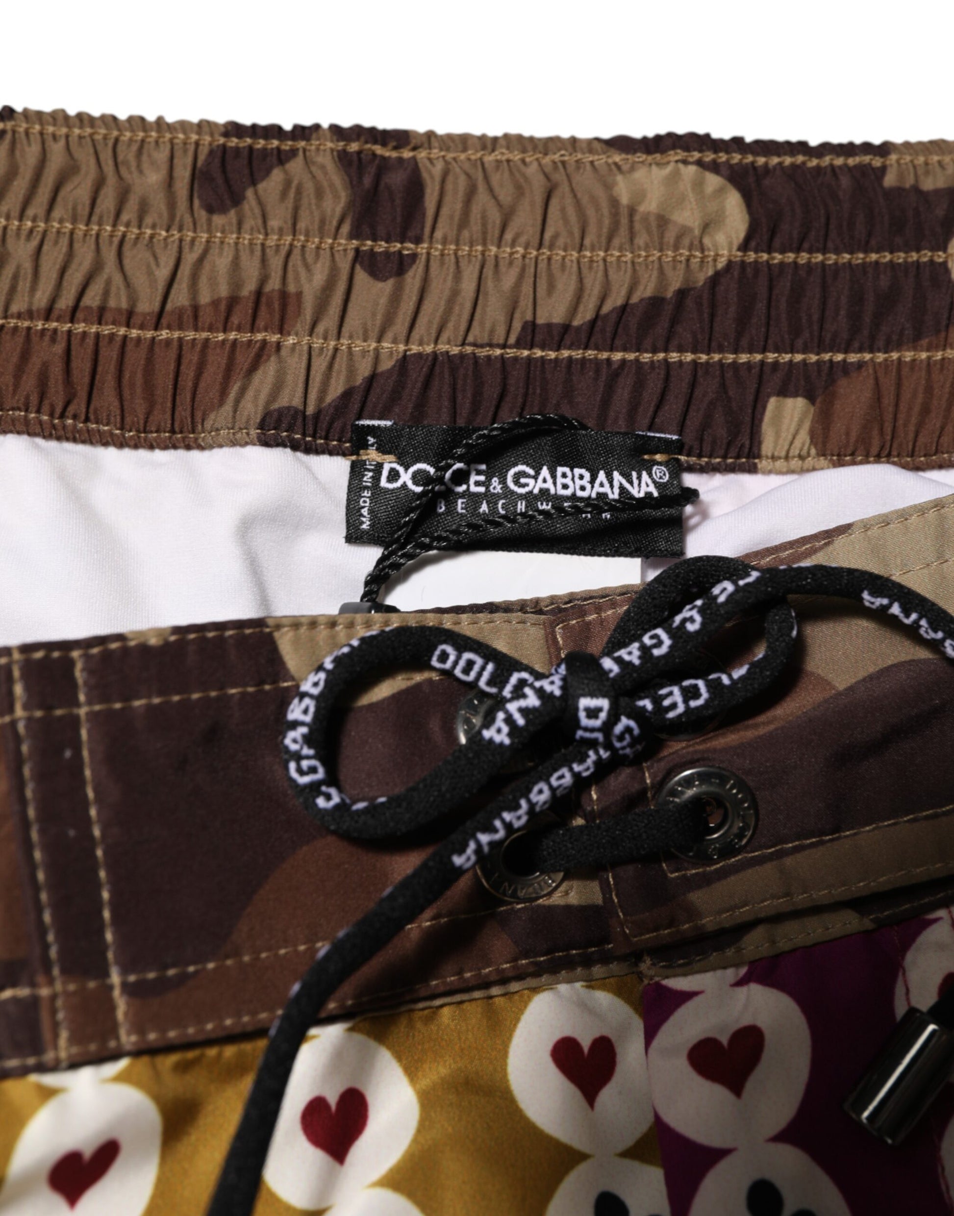 Camouflage swim trunks with black straps and a label that reads "DC Shoes"
