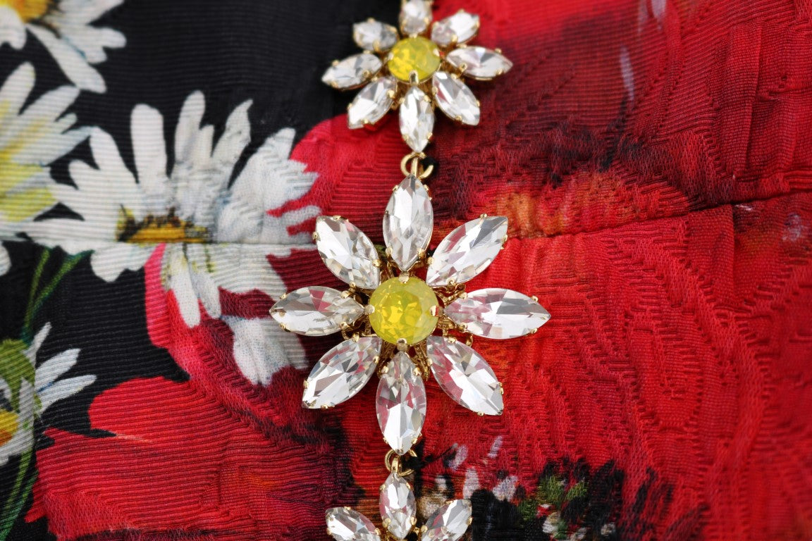 Jewelry brooch with yellow center stone surrounded by clear crystals on a red fabric background
