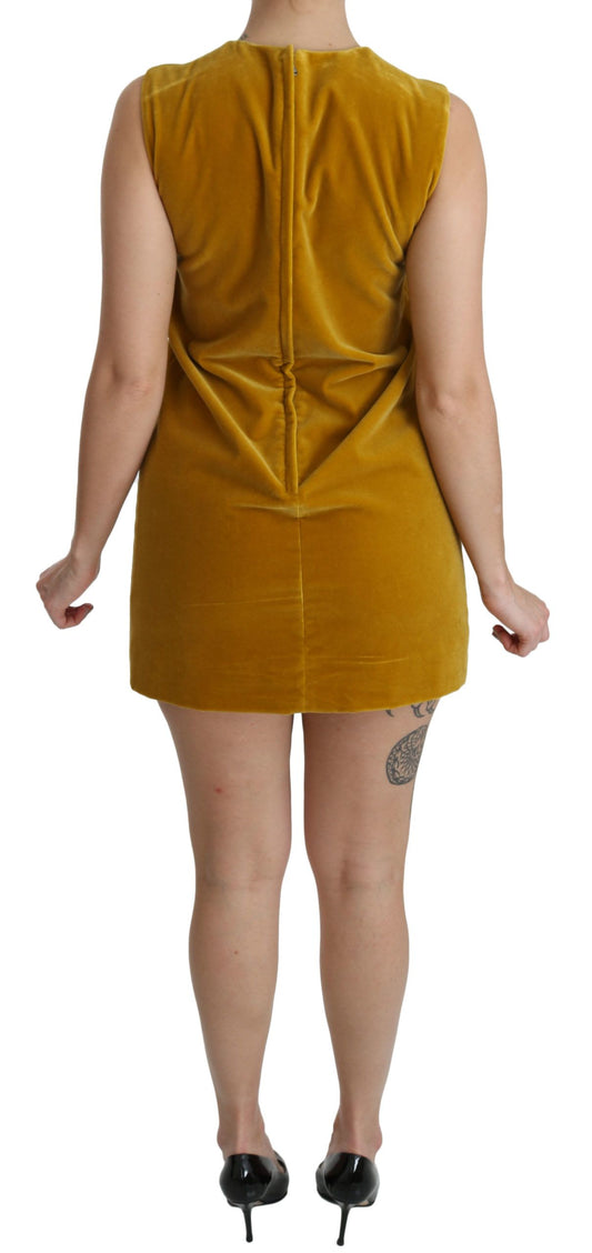 A woman wearing a mustard velvet stretch shift mini dress with short sleeves and a V-neckline
