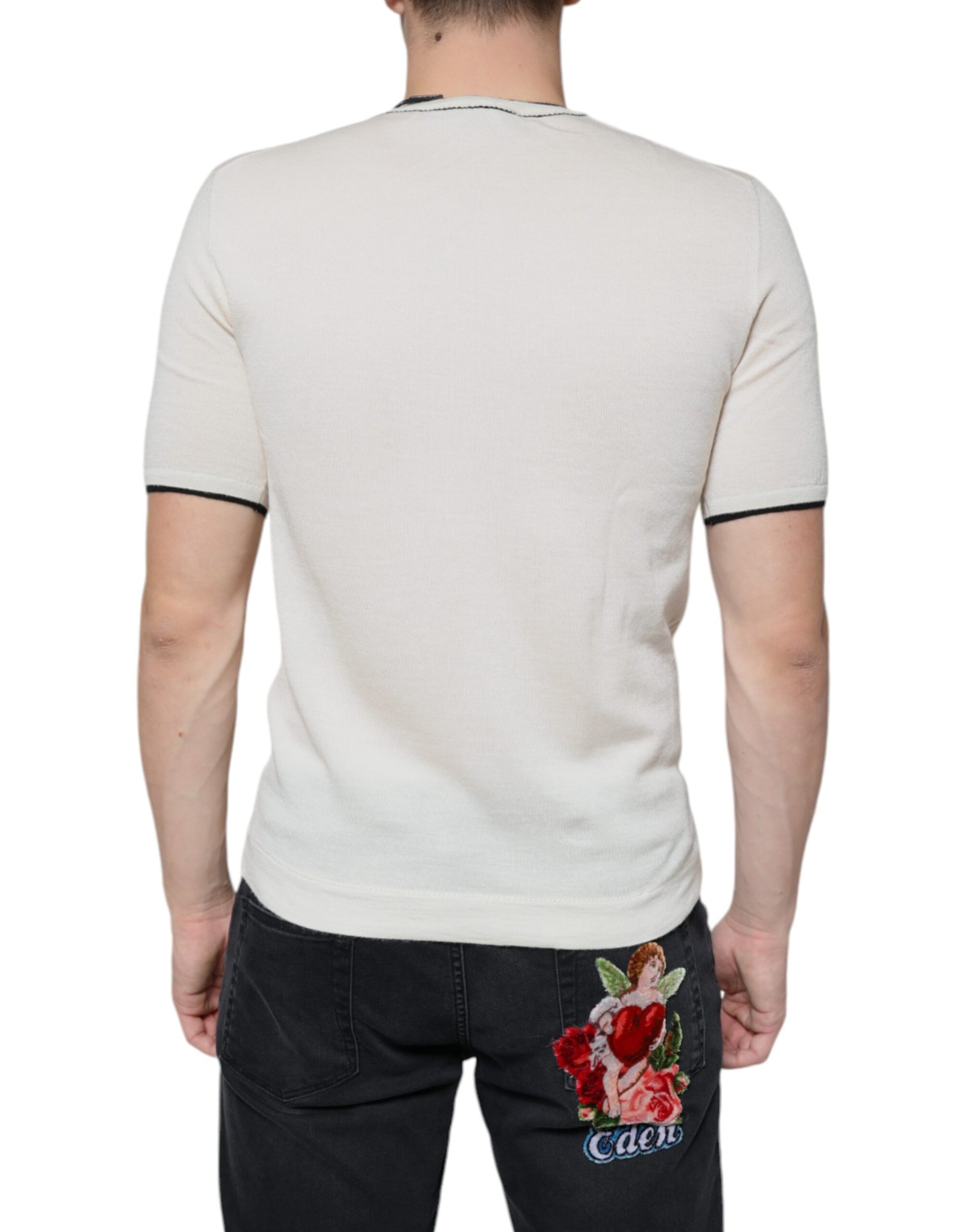 Man wearing white shirt with black stripe on sleeve and denim jeans with floral embroidery on back