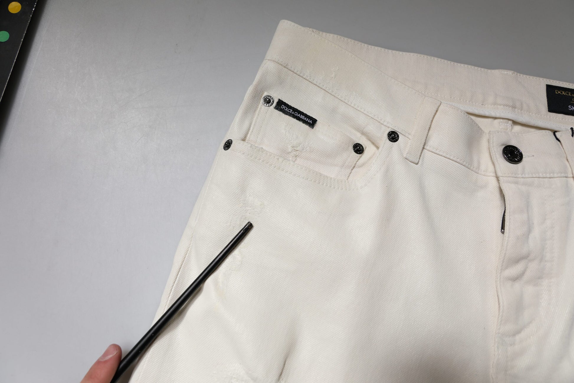 Pair of light beige trousers with black buttons and zipper