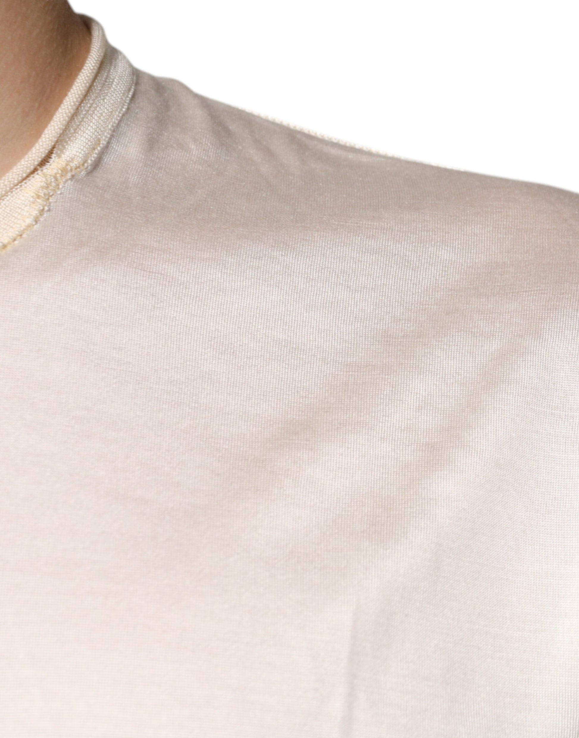 A person wearing a light beige or off-white garment that appears to be a shirt or blouse. The fabric has a su