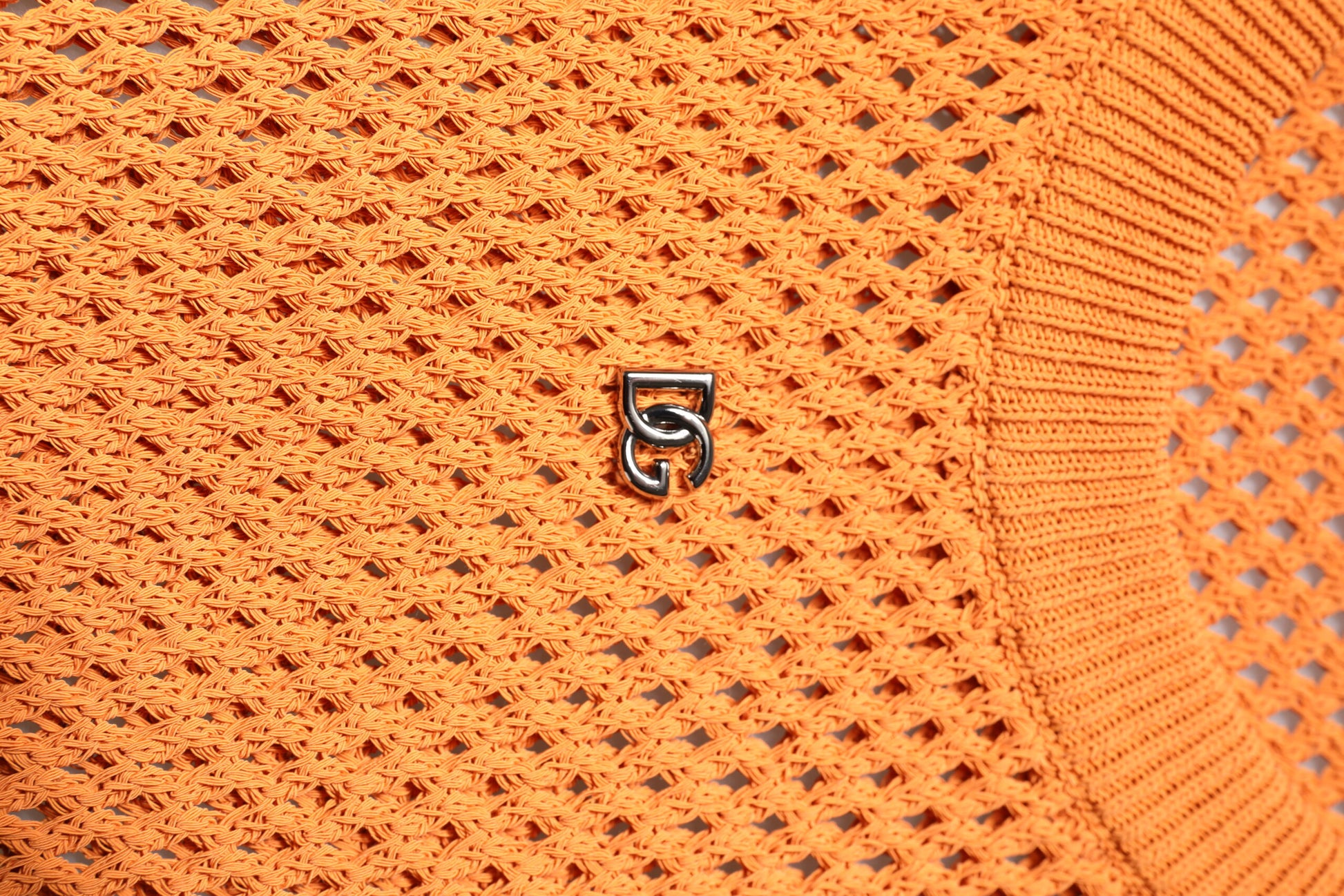 Orange knit sweater with a small black logo on front