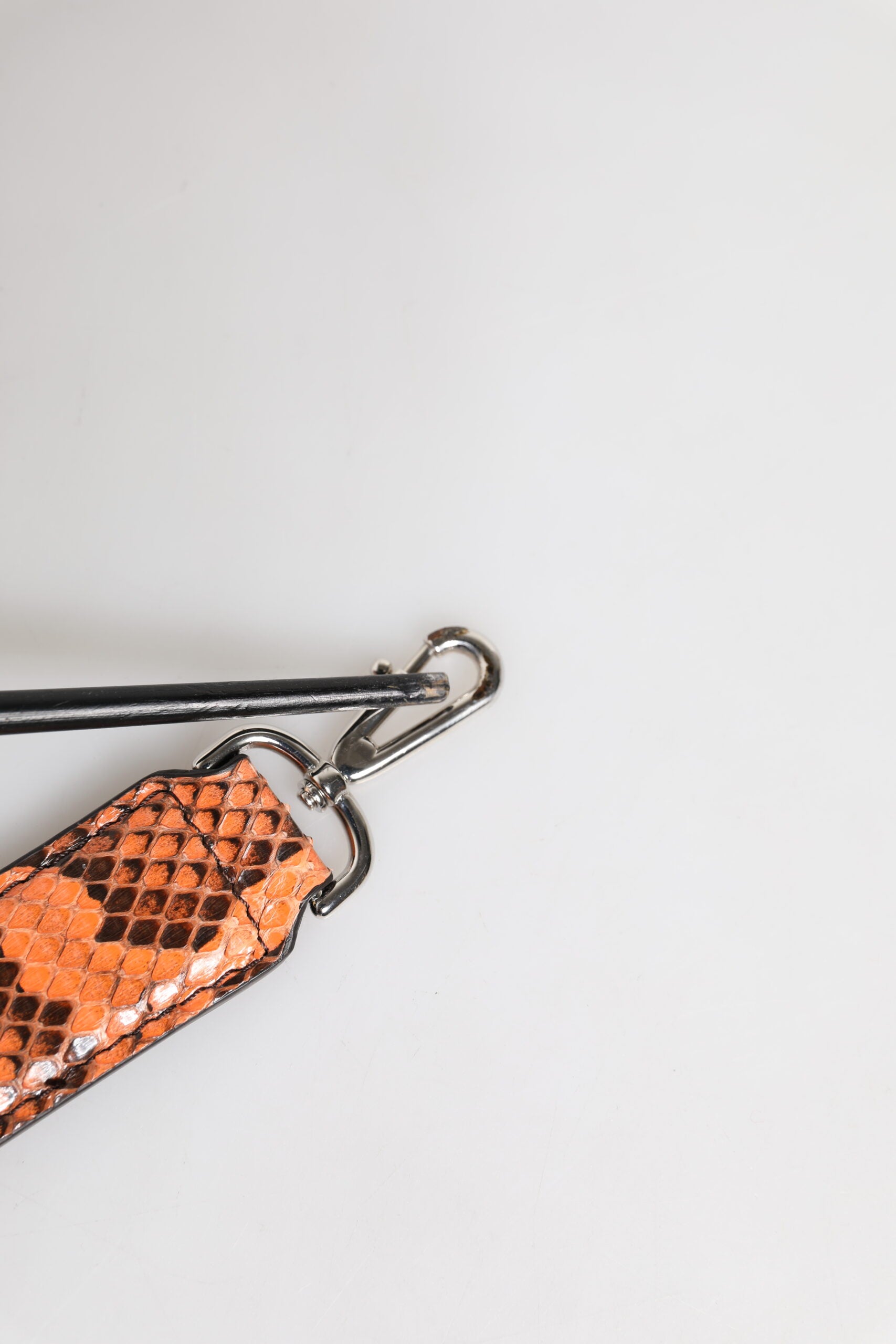 A keychain with a unique design featuring an orange and black patterned material that resembles snakeskin