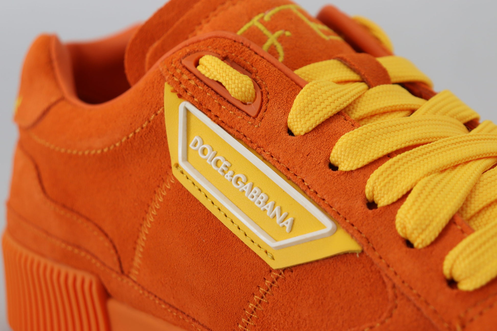 A pair of orange sneakers with yellow laces and a white logo on the side