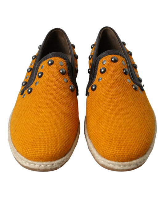 Pair of yellow shoes with black laces and silver studs on top