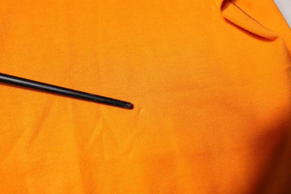 Black pin in orange fabric