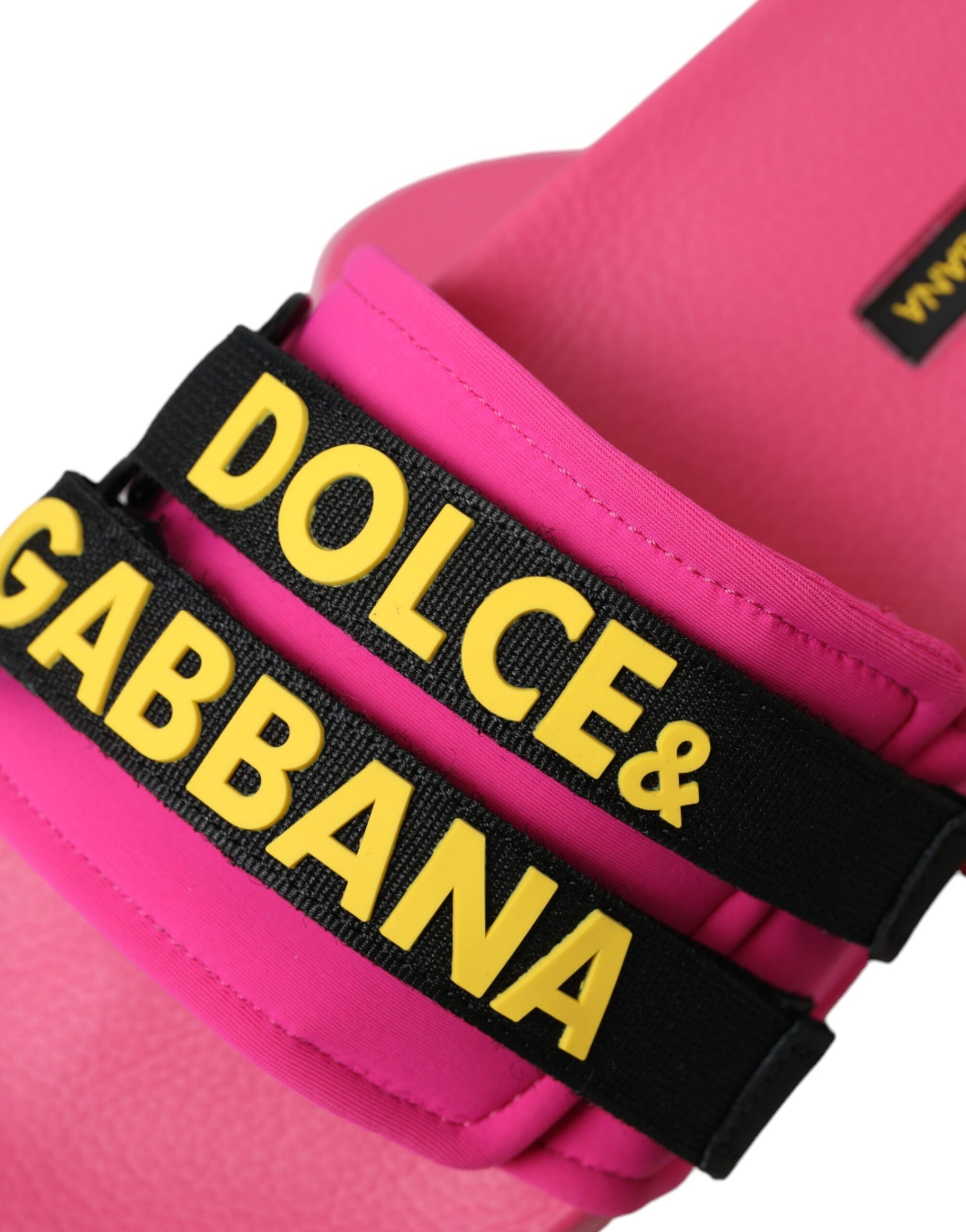Pink flip flops with black straps featuring yellow brand names