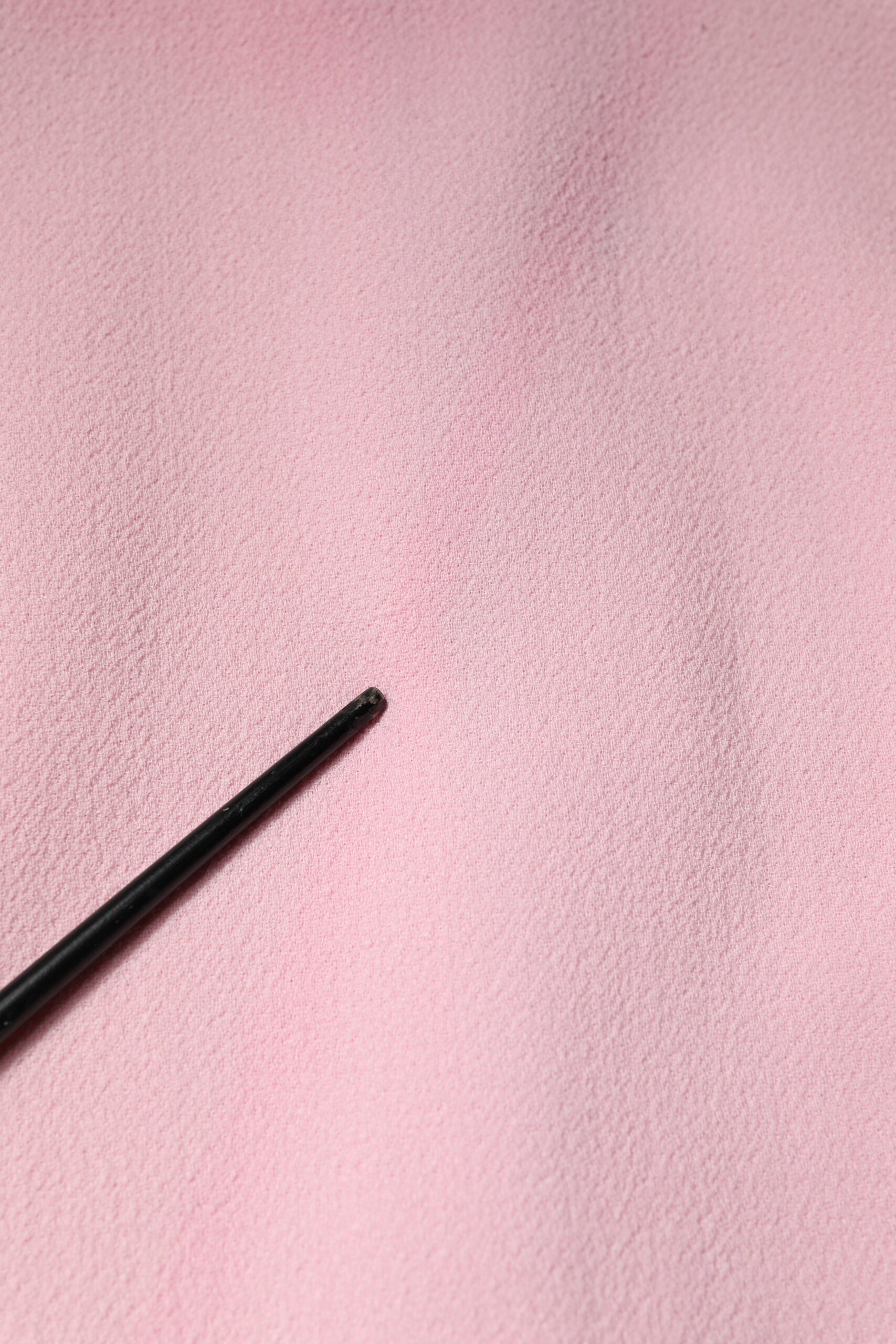 A black pen on a pink fabric surface