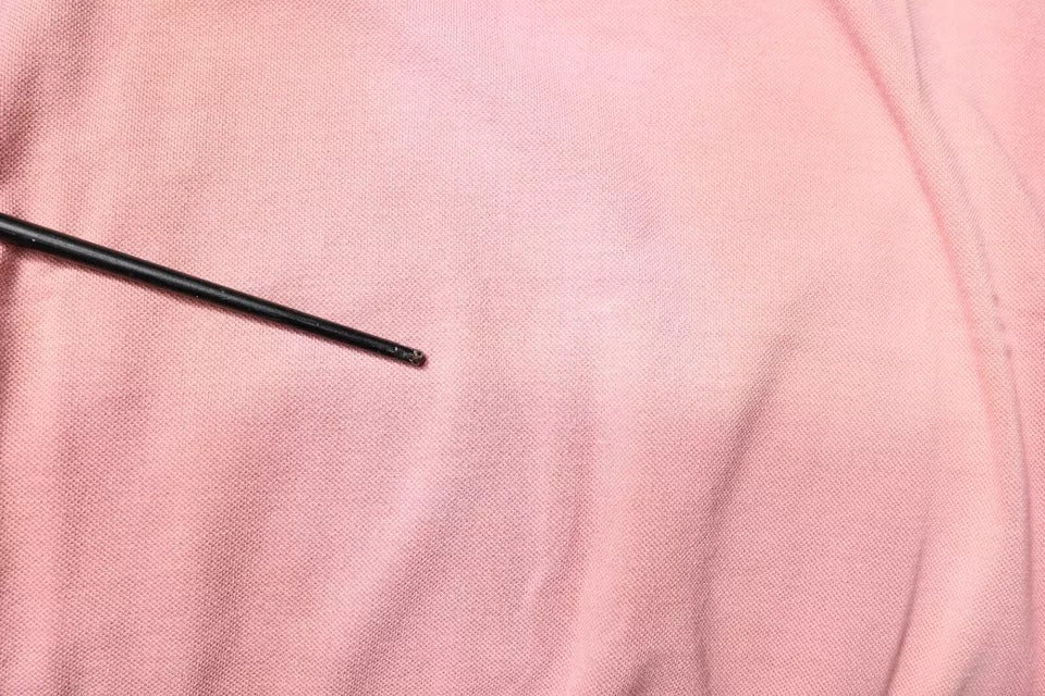 Black sewing needle on pink fabric