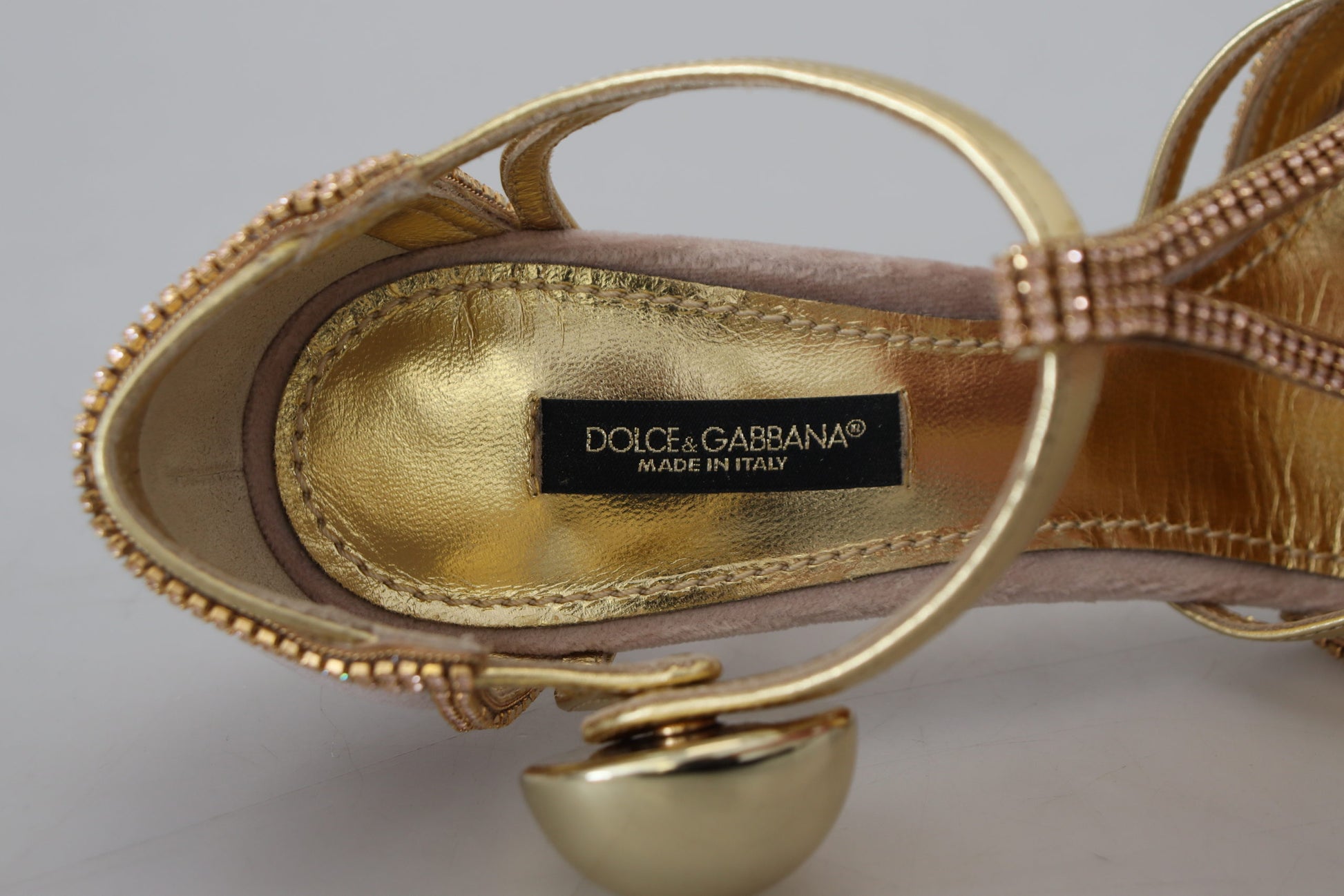 Gold high heel shoe with embellishments and a label that reads Dolce & Gabbana
