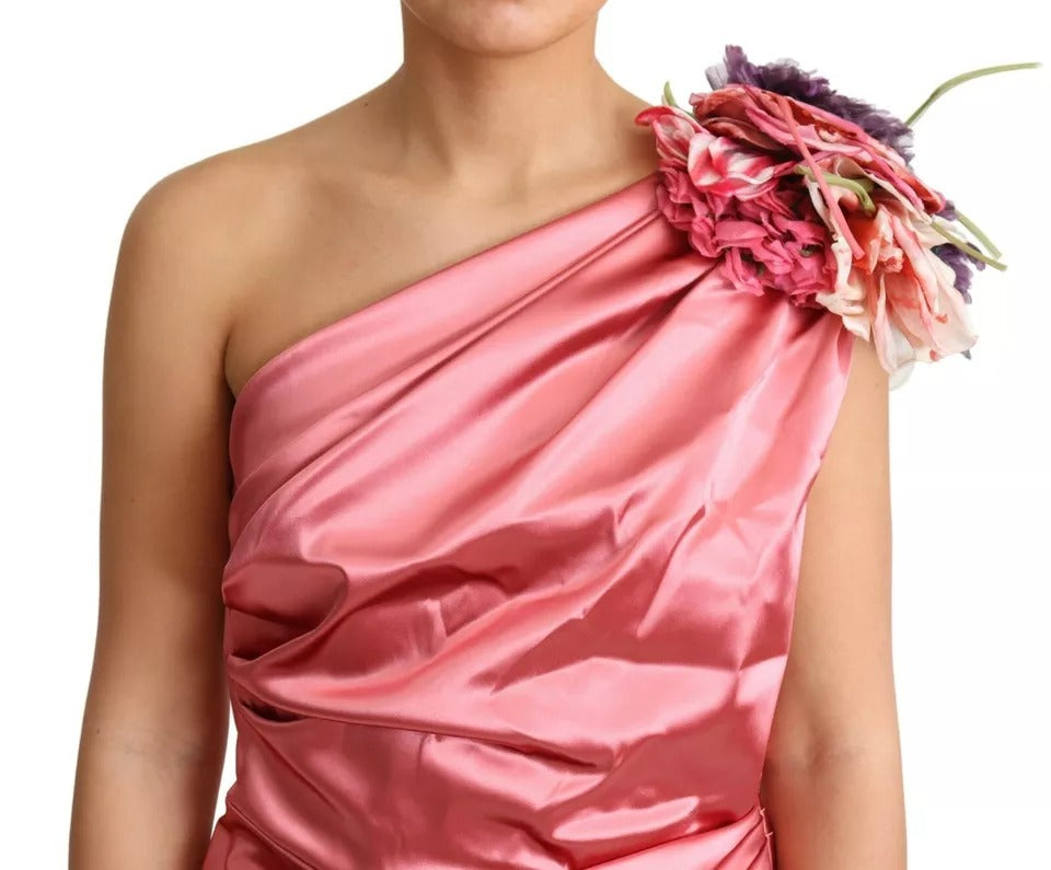 A pink draped midi dress with floral applique on the shoulder