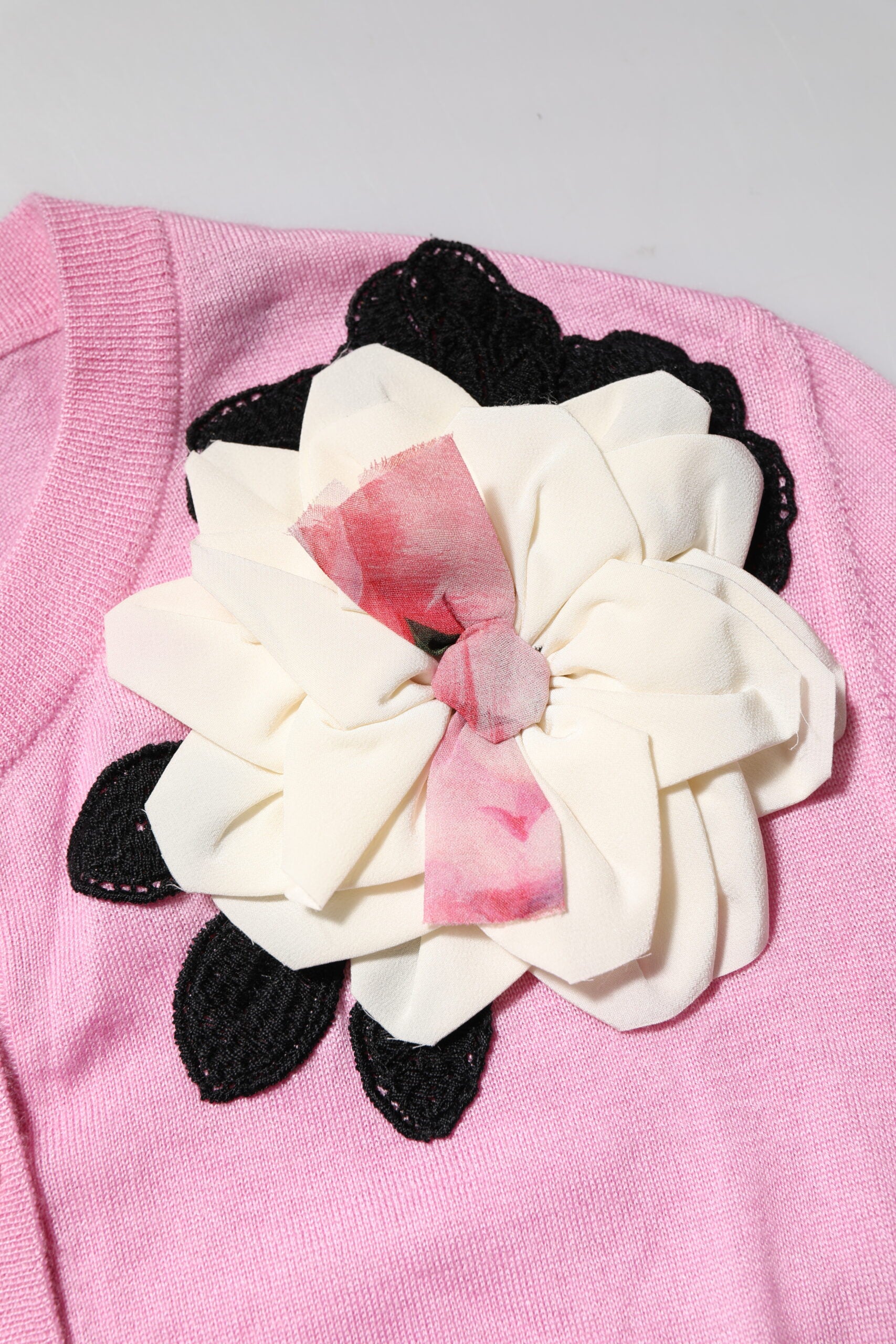 Pink fabric with black embroidery and a white flower applique