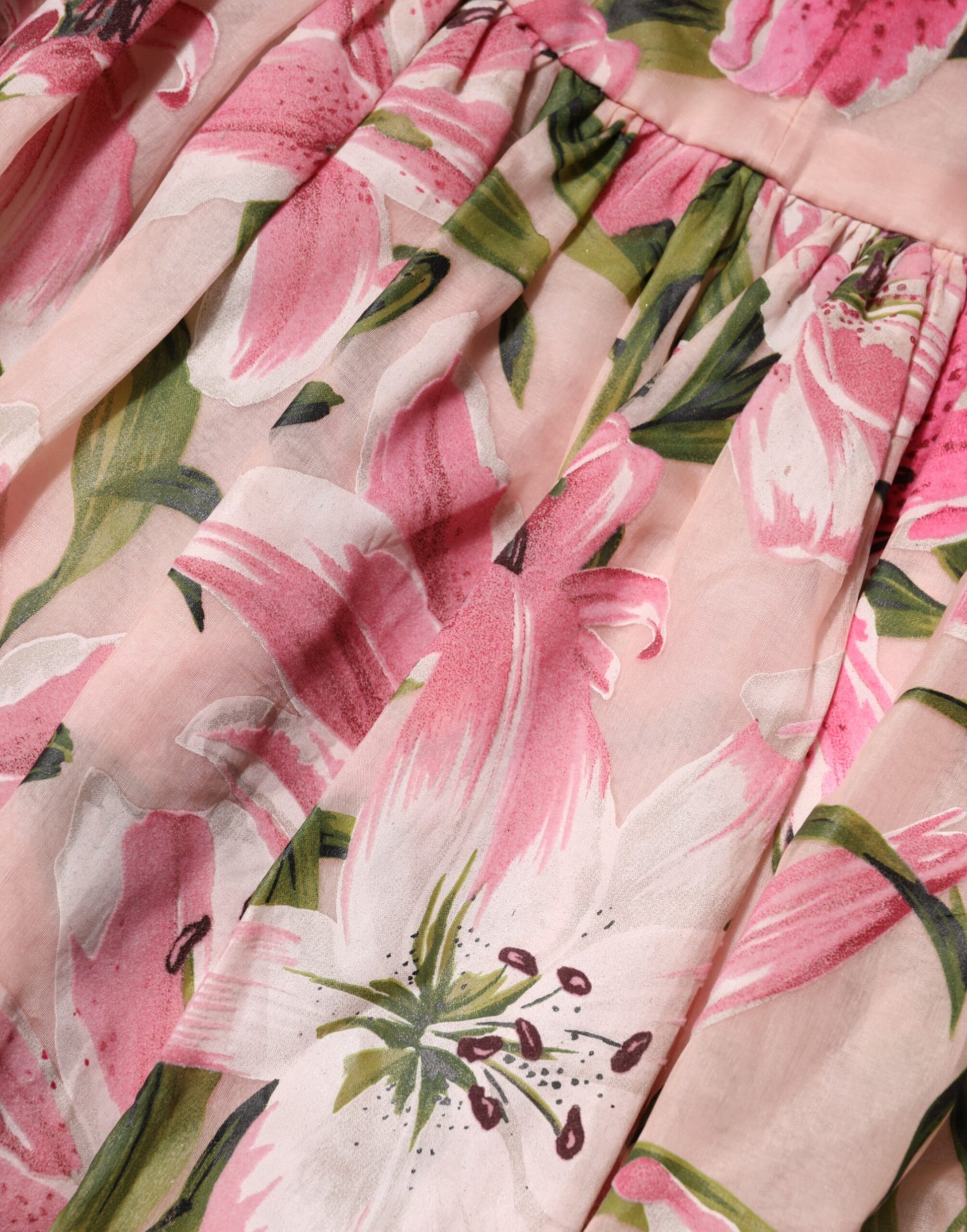 A pink floral print midi dress with lily design, sleeveless and featuring a ruffled hem